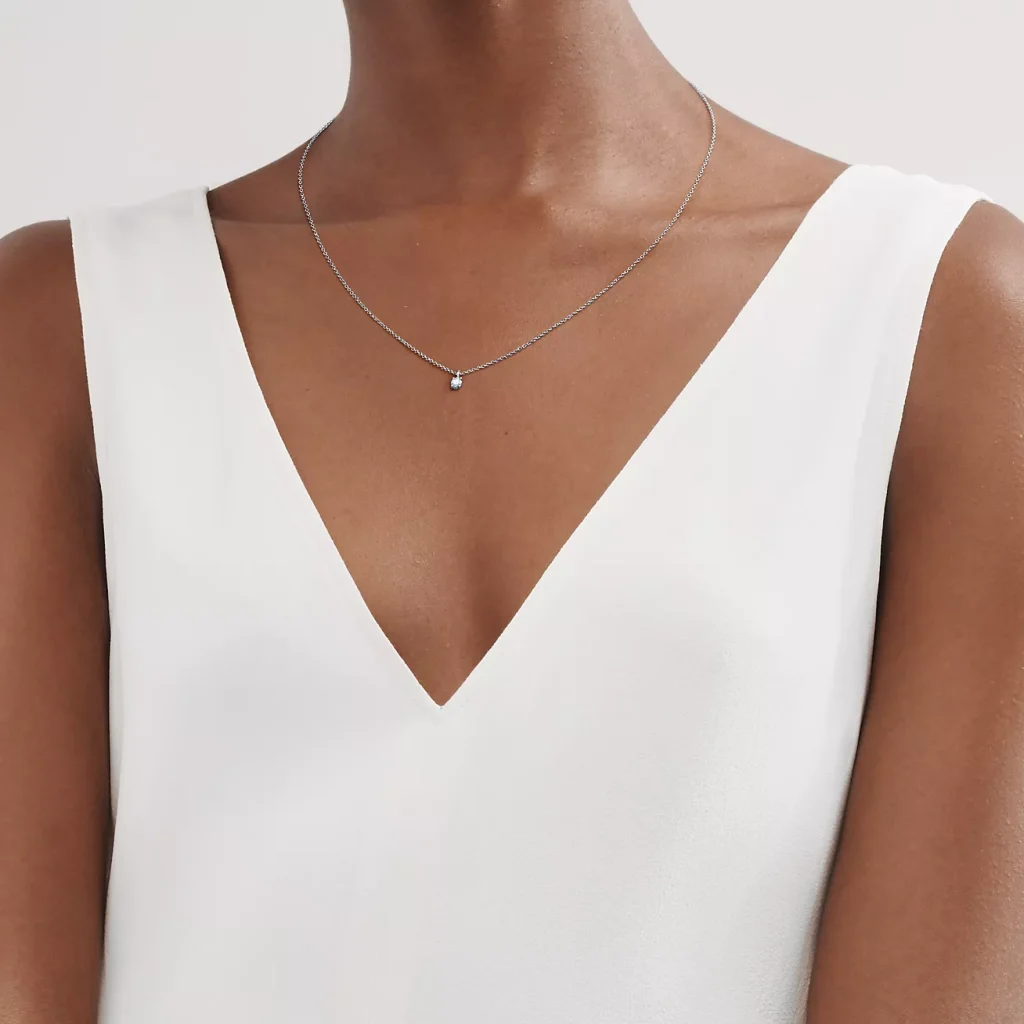 Women with white shirt wearing delicate silver necklace with a single pendant, ideal for a minimalist and elegant look.