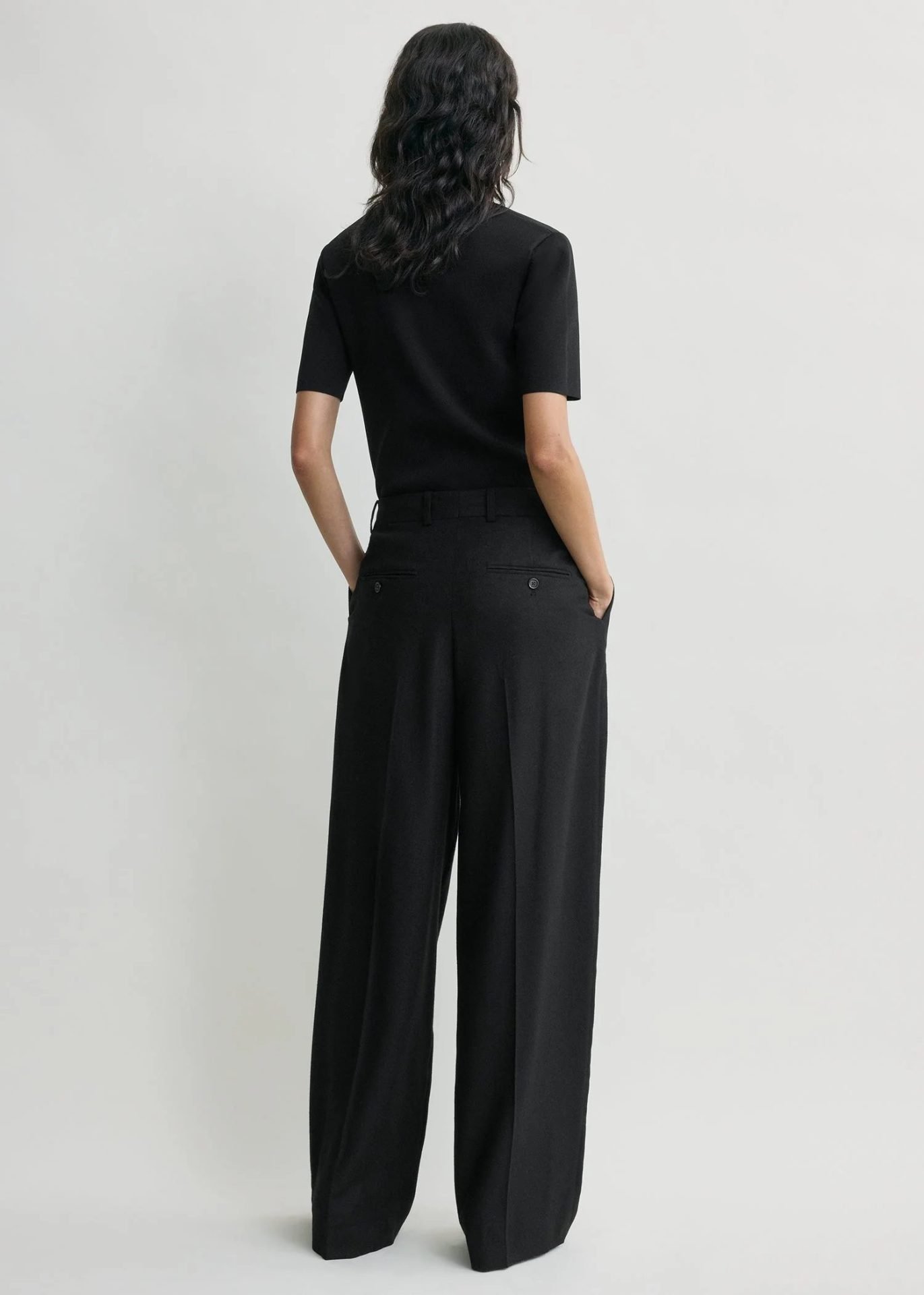Black tailored wide-leg trousers styled from the back, a timeless essential for Capsule Wardrobe 2026 with clean lines and elegant fit
