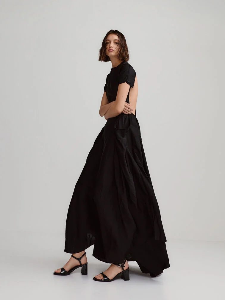 Woman in a flowing black dress wearing block heel sandals while walking gracefully. Heels That Are Actually Comfortable and Elegant
