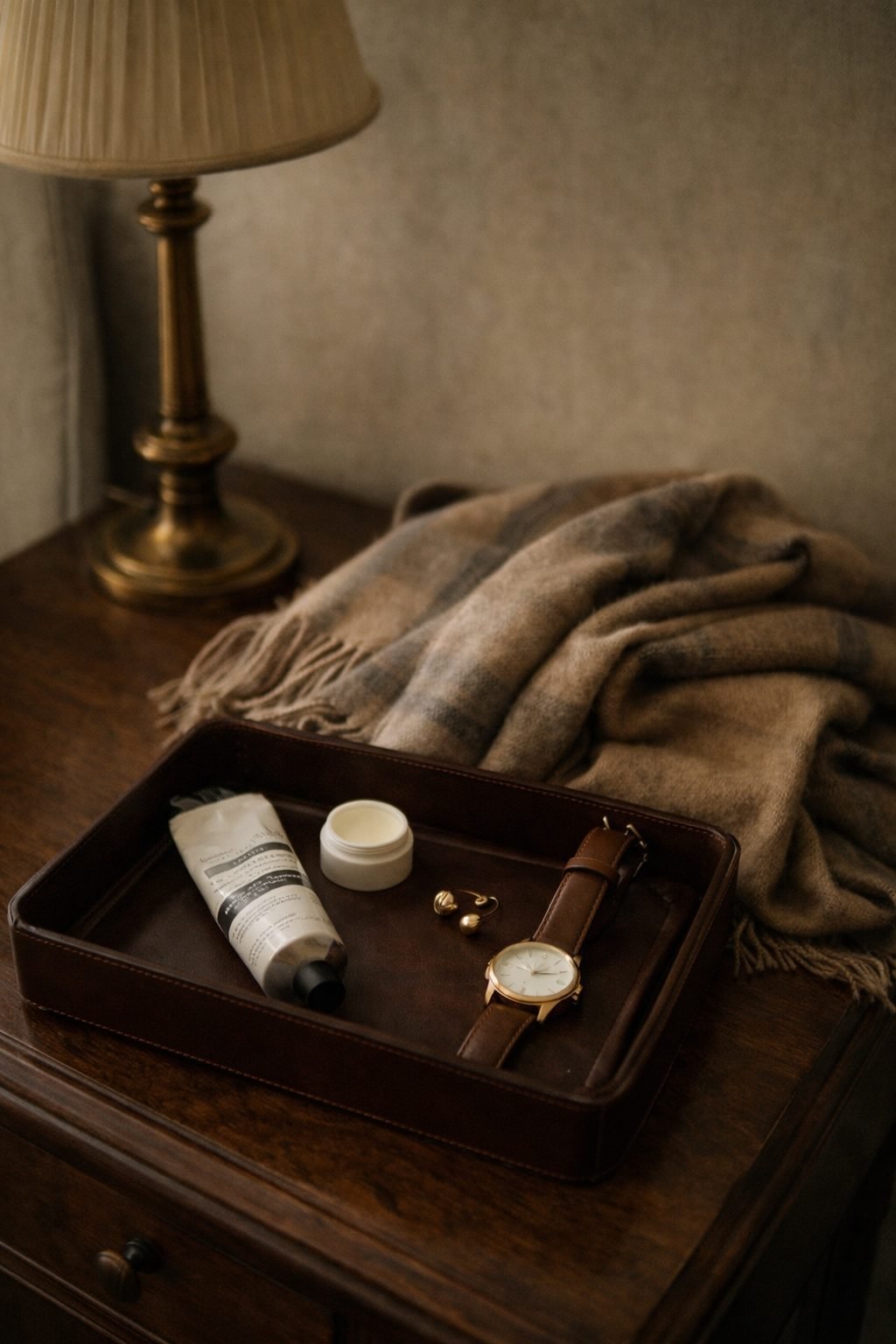 Leather tray with watch, hand cream, and earrings styled for travel, capturing quiet luxury details and How to Dress on a Plane well