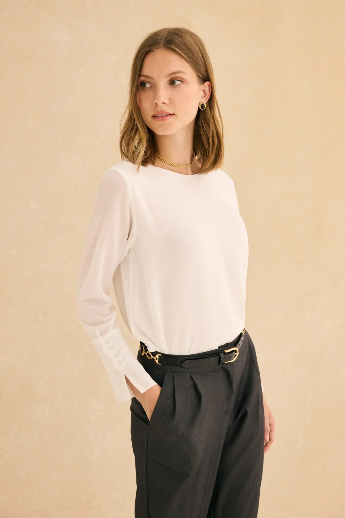 Woman wearing a cream blouse and tailored black trousers, classic polished outfit inspiration for What to Wear When Meeting His Family