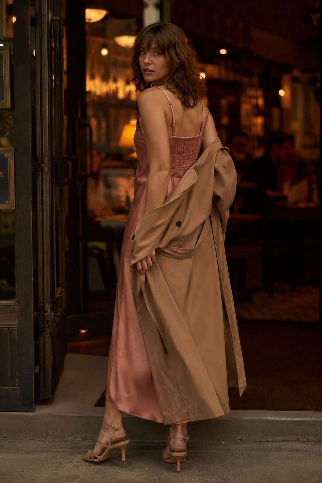 trench coat outfit for evening: camel trench coat over a silk slip dress with black strappy heels