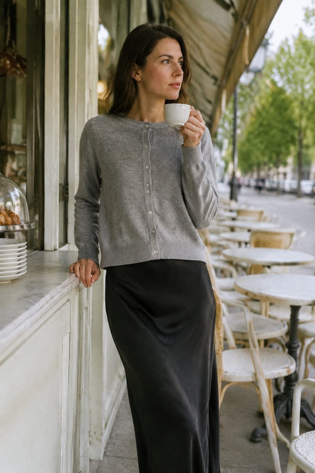 affordable quiet luxury coffee run outfit: grey cardigan buttoned backward over a black slip skirt