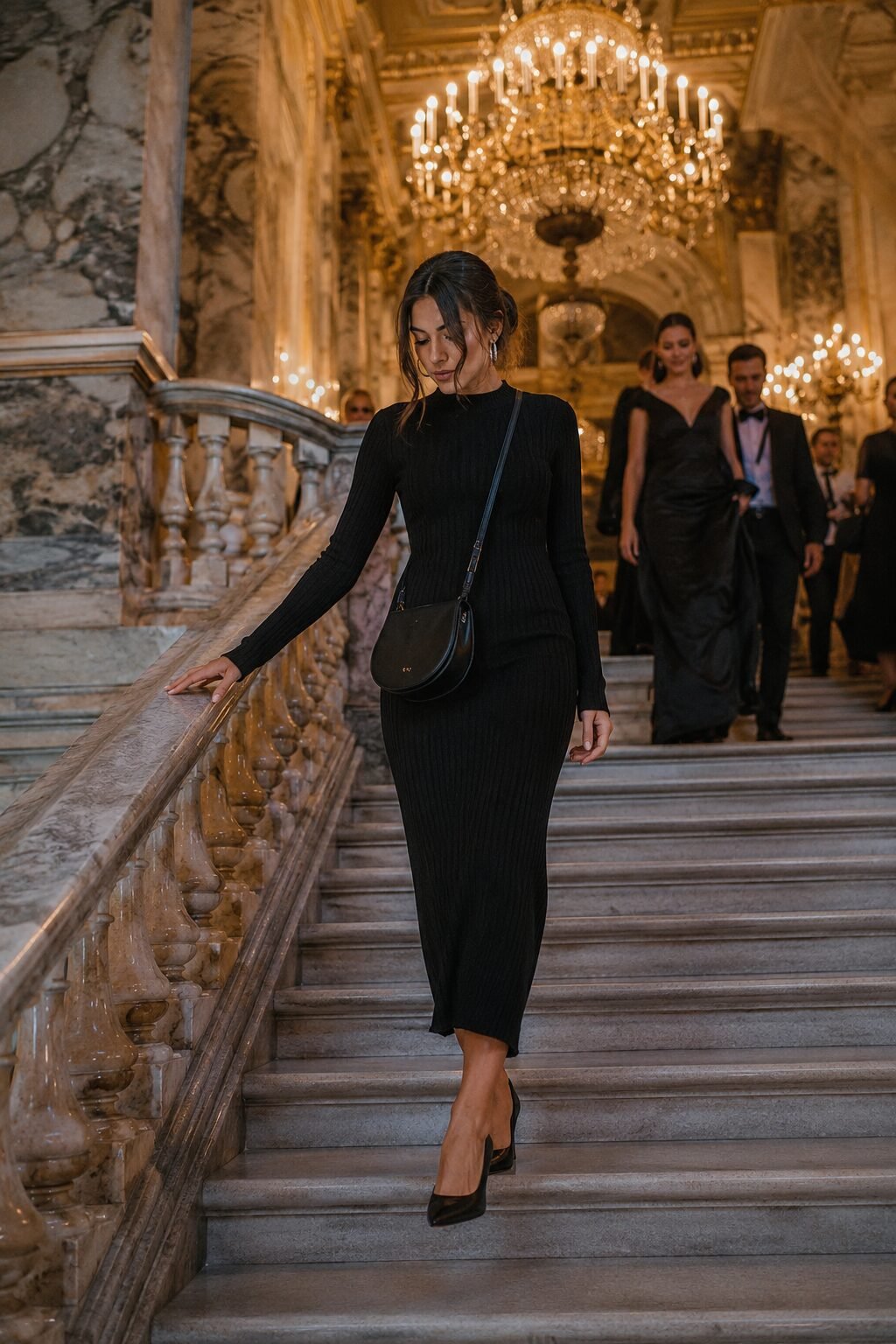woman wearing a black knit midi dress and carrying a structured black evening bag for an upscale Halloween gala outfit