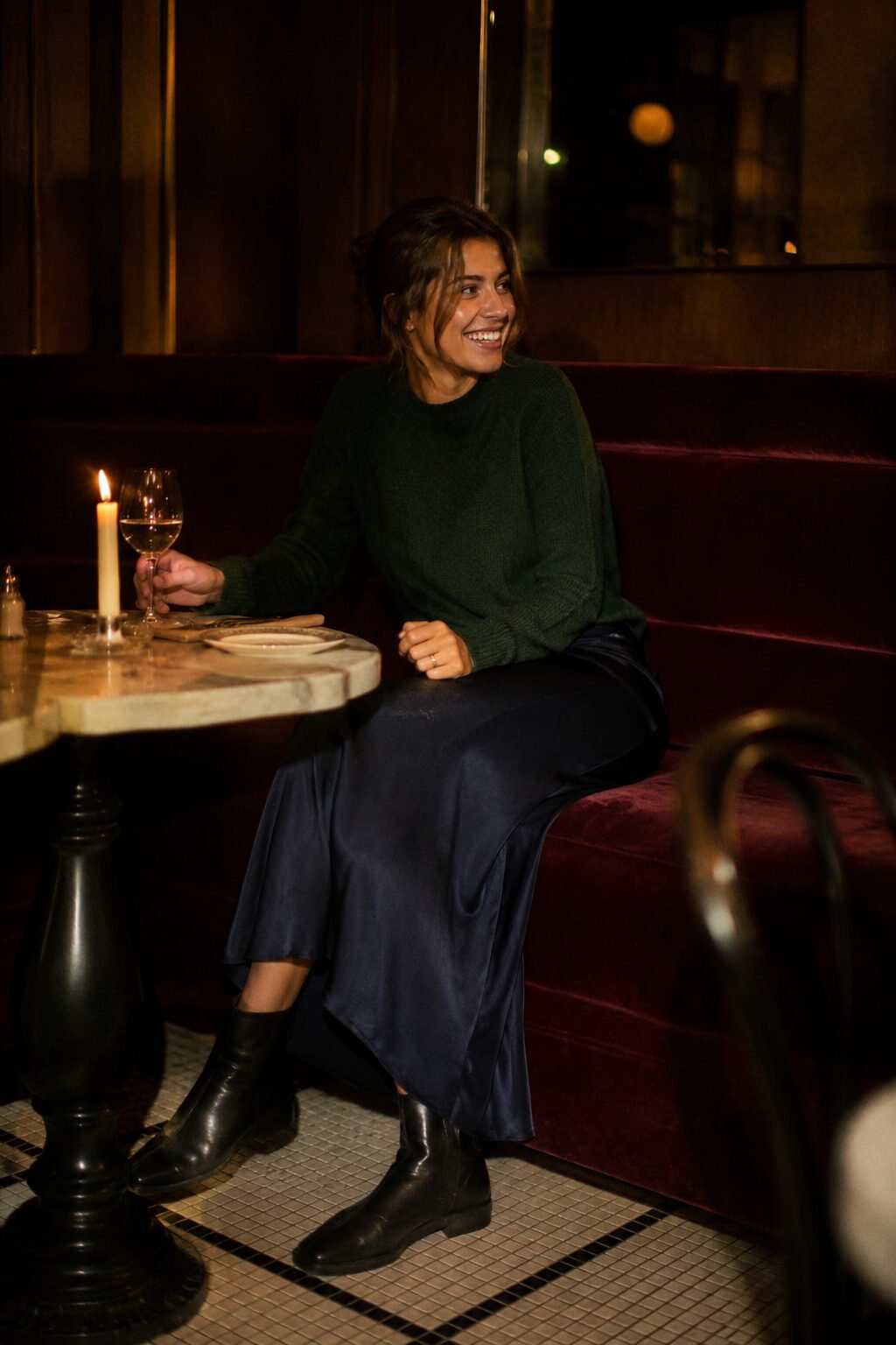fall capsule wardrobe dinner outfit: forest green sweater tucked into a navy silk skirt with black ankle boots