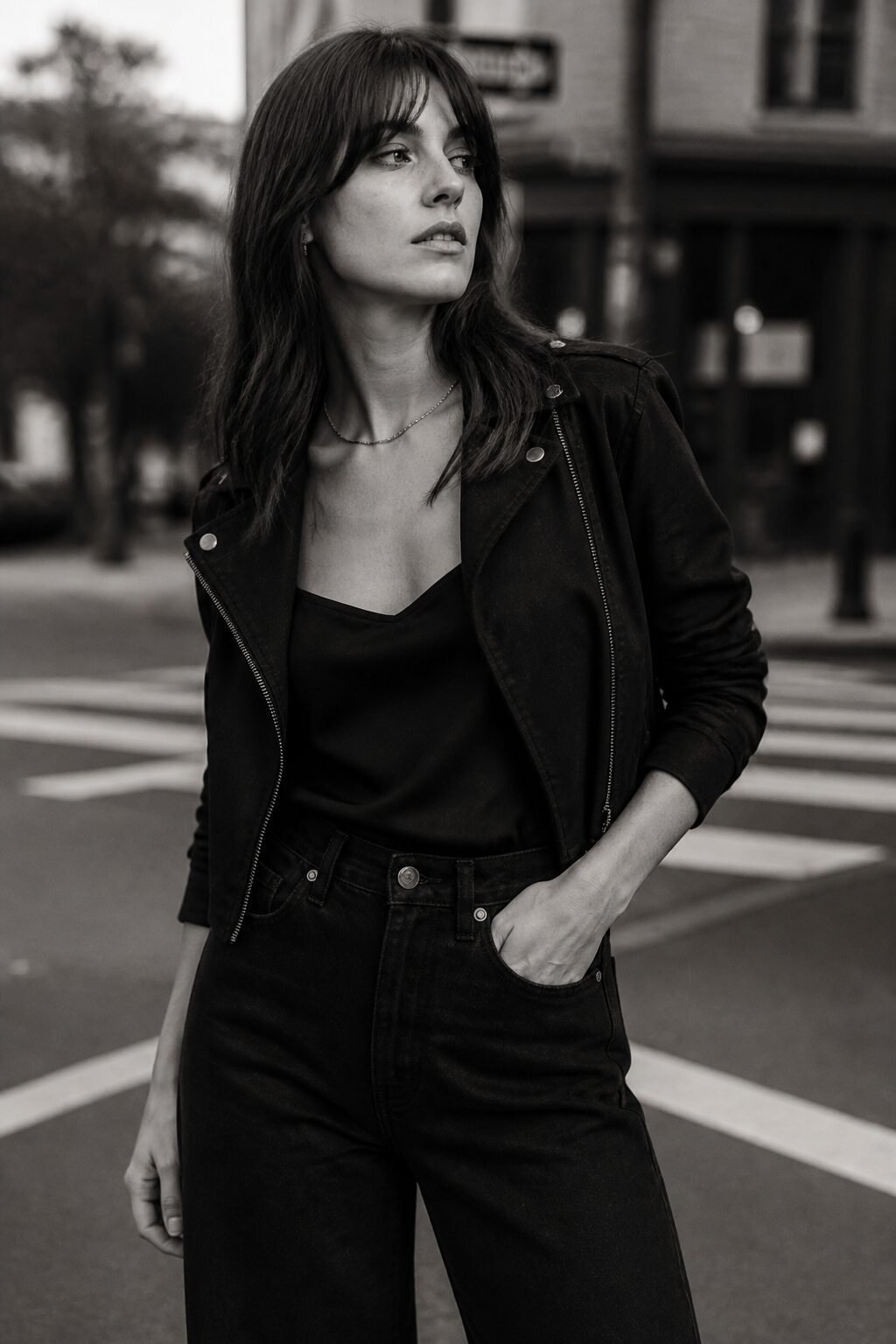 Carolyn Bessette jeans outfit: black cropped moto jacket and silk camisole with wide-leg denim for an evening out