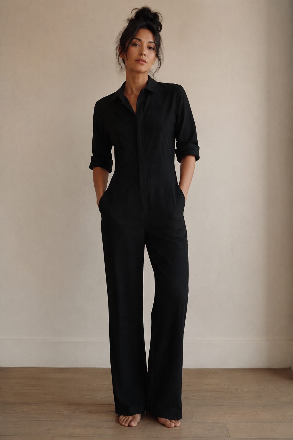 woman in a 90s minimalist outfit wearing a black tailored jumpsuit with sleeves rolled and no belt