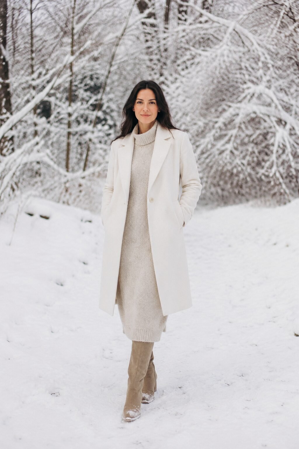 family christmas outfits in a snowy photo with shared winter-white outerwear over soft neutral layers