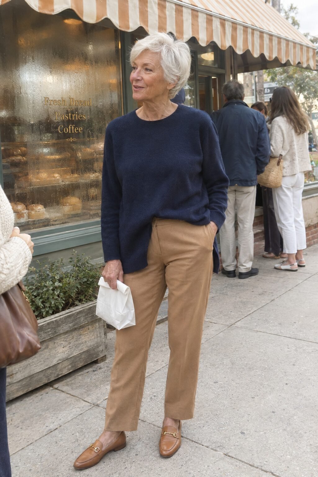 how to style a tunic for women in their 70s: navy crewneck tunic front-tucked into camel trousers with tan loafers