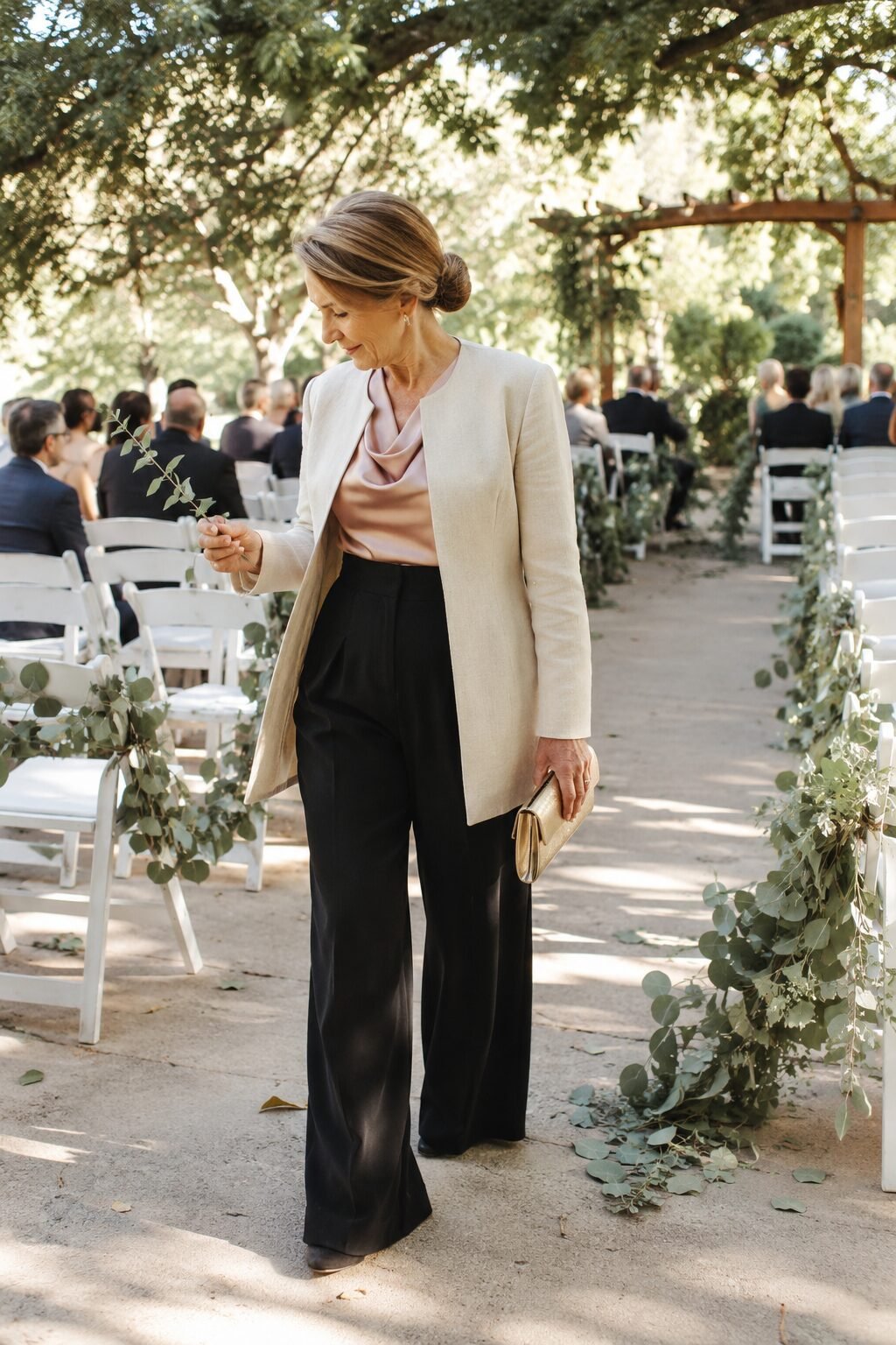 mother of the groom ceremony outfit: black wide-leg trouser, blush satin top, ivory jacket, and gold clutch