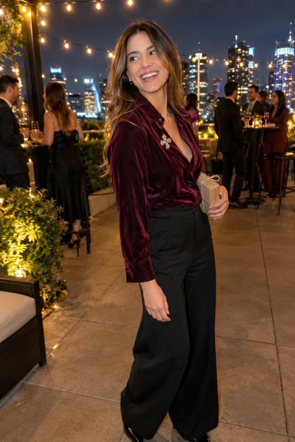 burgundy velvet shirt and black wide-leg trousers Christmas party outfit with a gold and crystal brooch at the collar