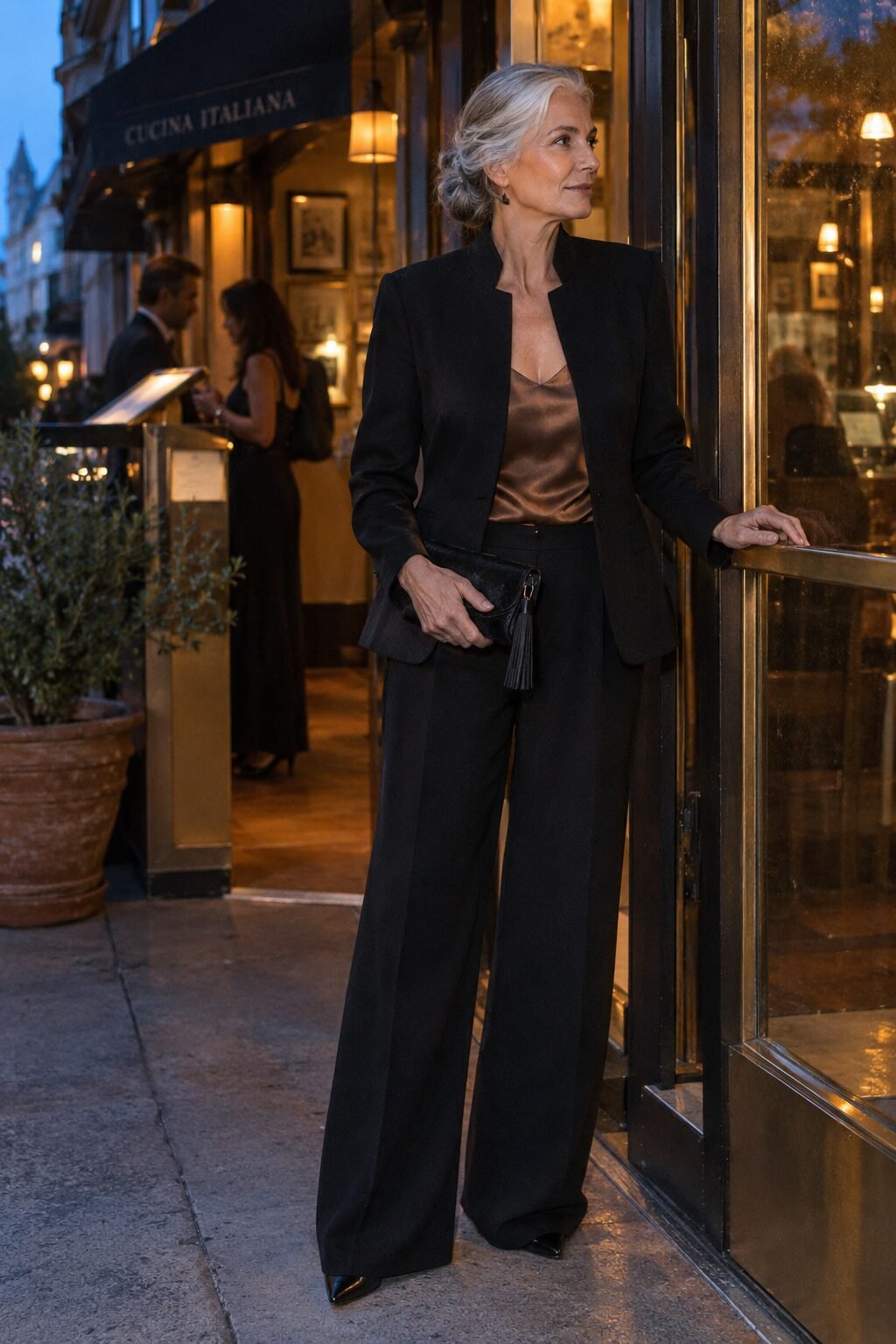 black tie mother of the groom pantsuit: black stand-collar blazer, wide-leg trousers and satin clutch