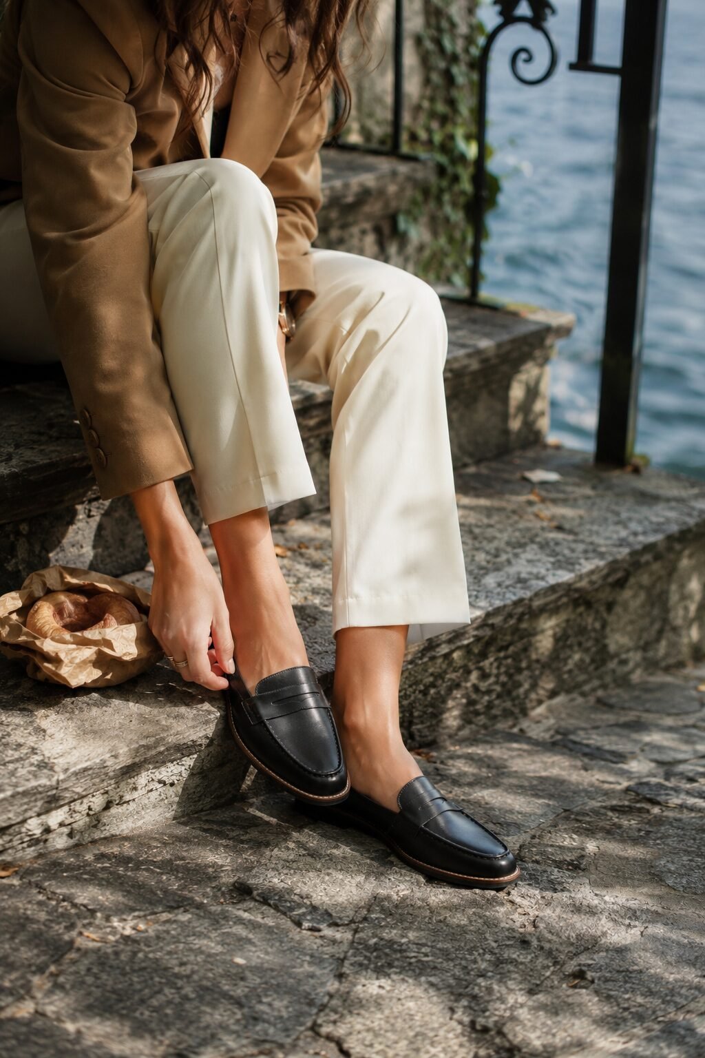 Close-up of a woman's feet wearing black leather loafers on cobblestone