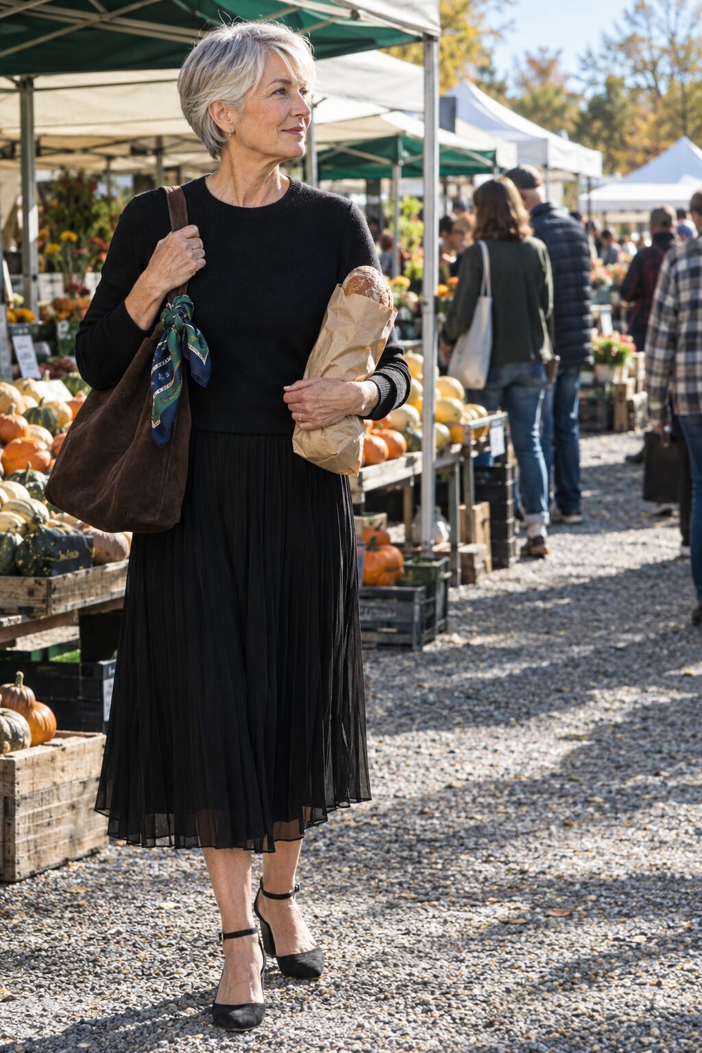 how to style a silk scarf tied to the strap of a suede shoulder tote with a black pleated midi skirt