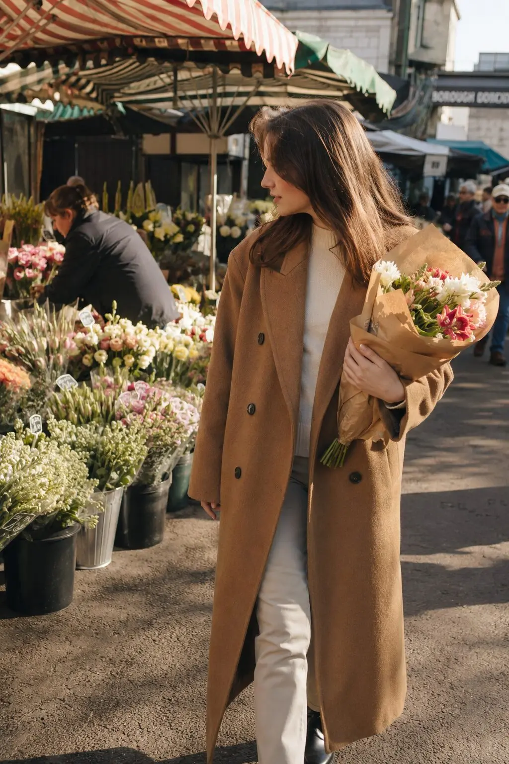 camel wool coat worn open at an outdoor flower market