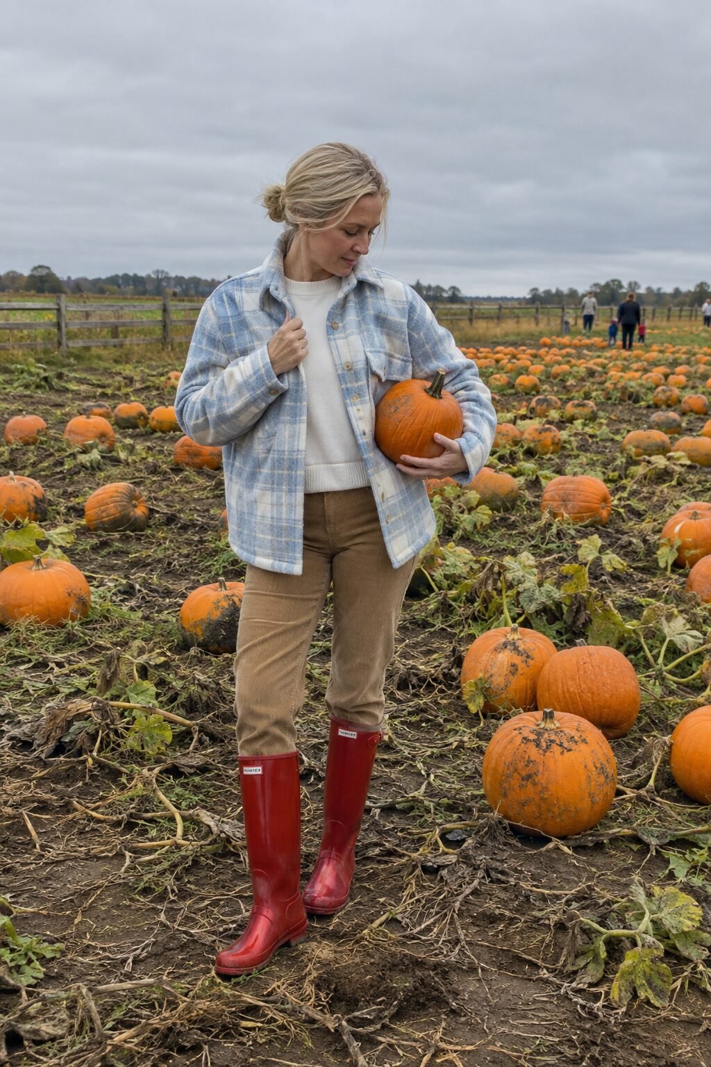 old money countryside fall outfit: plaid shirt-jacket, ivory cashmere sweater, and red wellington boots at a pumpkin patch