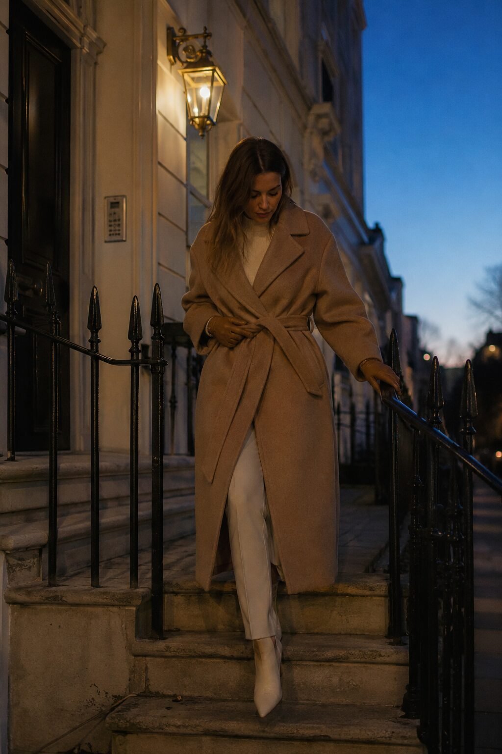 quiet luxury halloween outfit: camel wrap coat over cream knit and tapered trousers
