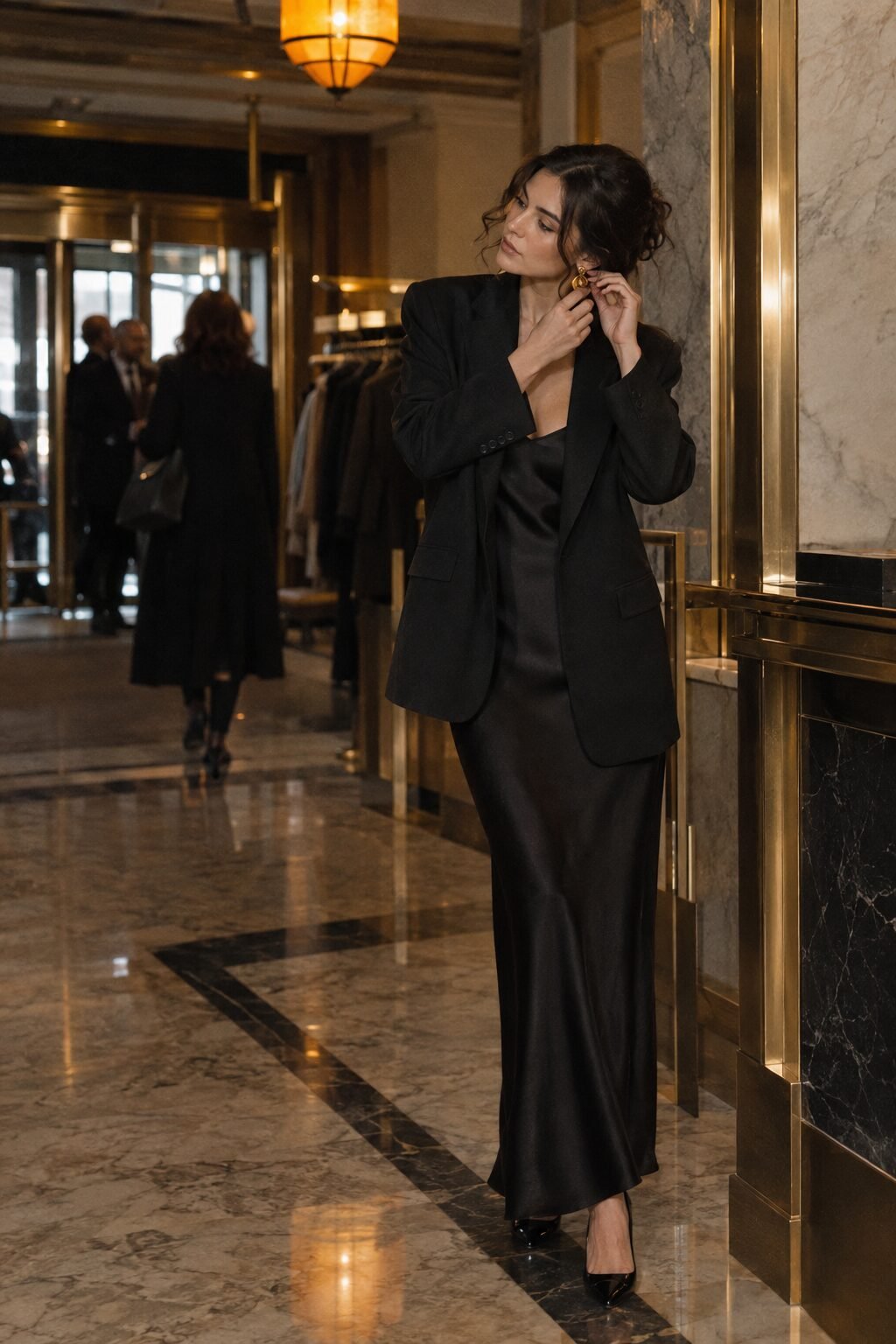 work holiday party outfit: black silk slip dress under an open blazer with gold statement earrings