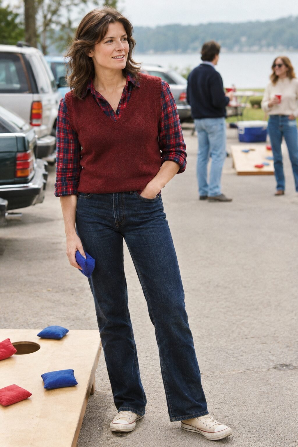 preppy old money tailgate outfit: red and navy flannel shirt layered under a red wine sweater vest, with deep rinse denim