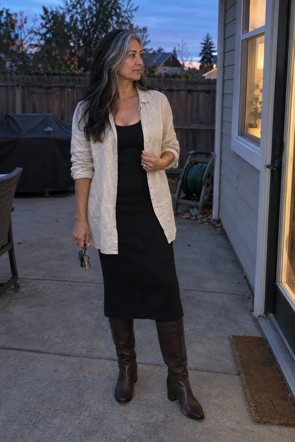 how to style a linen shirt worn open like a jacket over a black knit scoop-neck midi dress with dark-brown knee-high boots