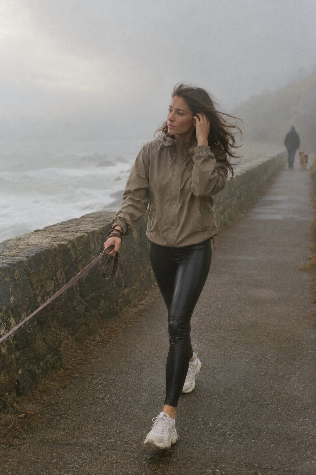 dog walk rainy day outfit: taupe water-repellent windbreaker and black faux leather leggings