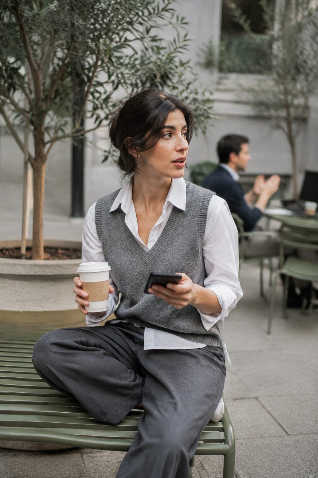 casual Friday business trip outfit: grey merino sweater vest over white button-down and technical trousers