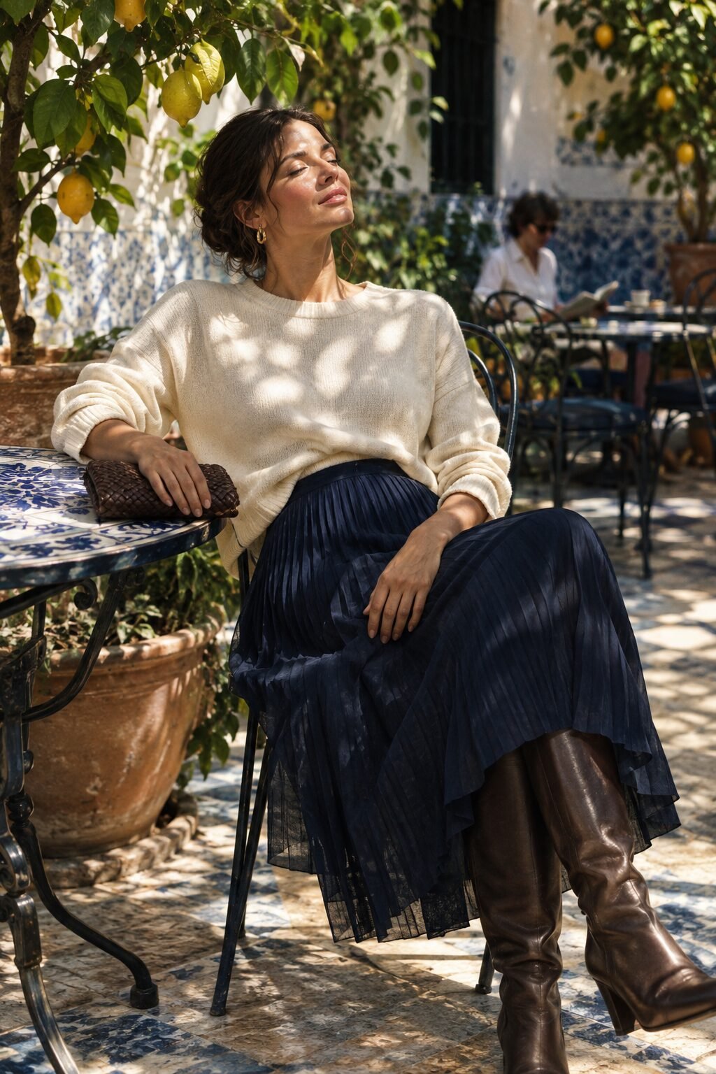 fall brunch outfit: navy pleated midi skirt with a cream sweater and dark brown knee-high boots