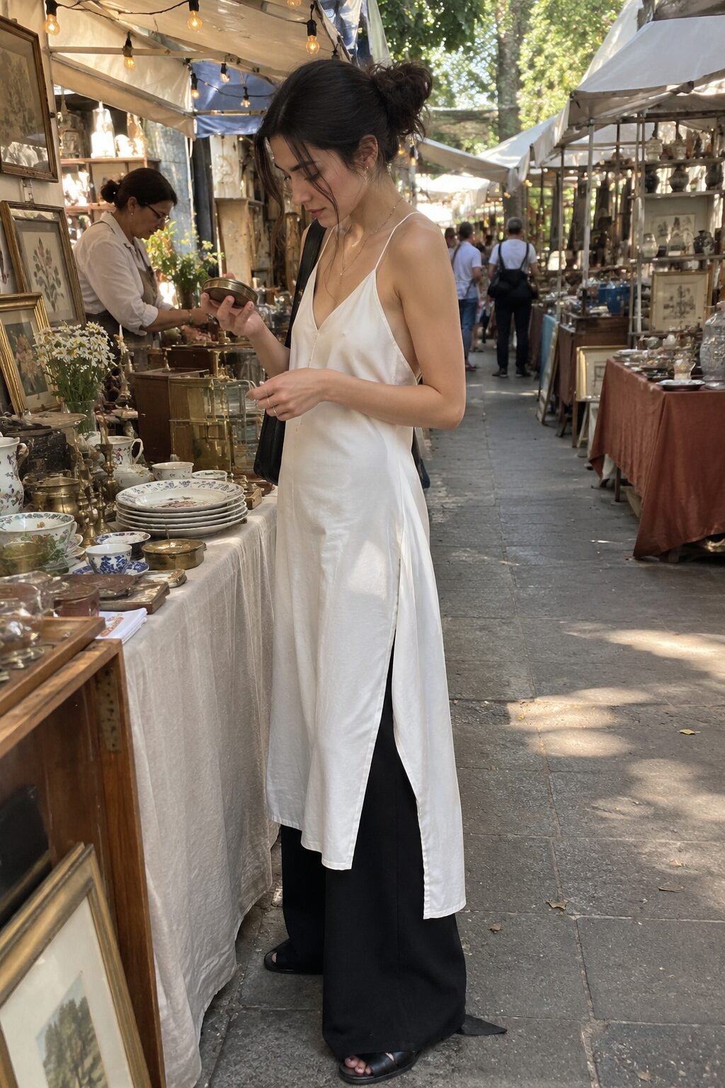 woman wearing a white slip dress over black wide-leg trousers, trend-forward fall layering with a summer dress