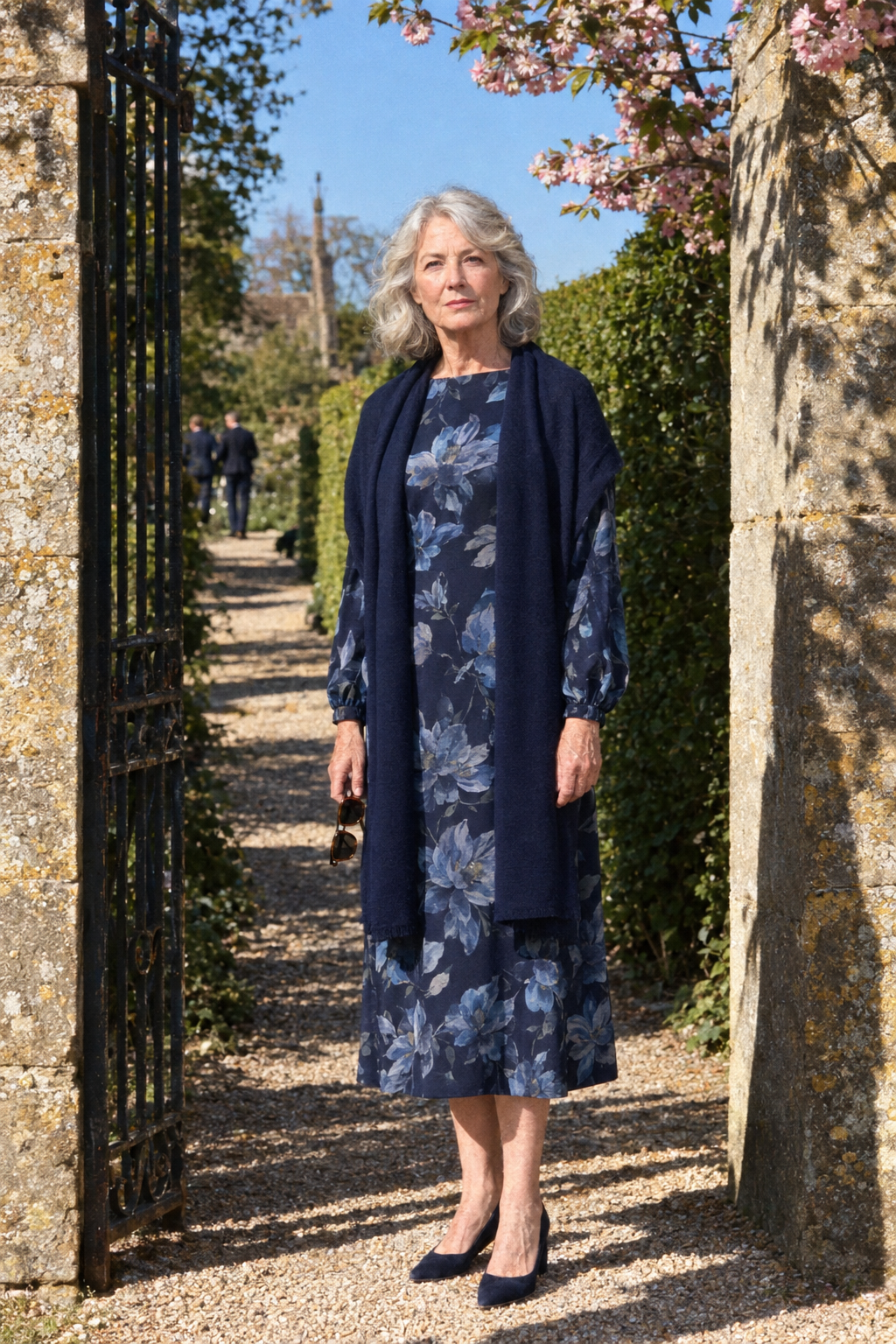 wedding guest outfit for women in their 70s: navy floral long-sleeve midi dress with navy suede block-heel pumps and a navy cashmere wrap