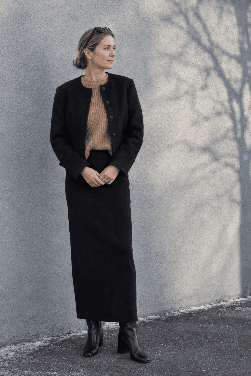 winter outfit for women over 40: black cropped boxy jacket, camel fisherman sweater, black column maxi skirt and black ankle boots