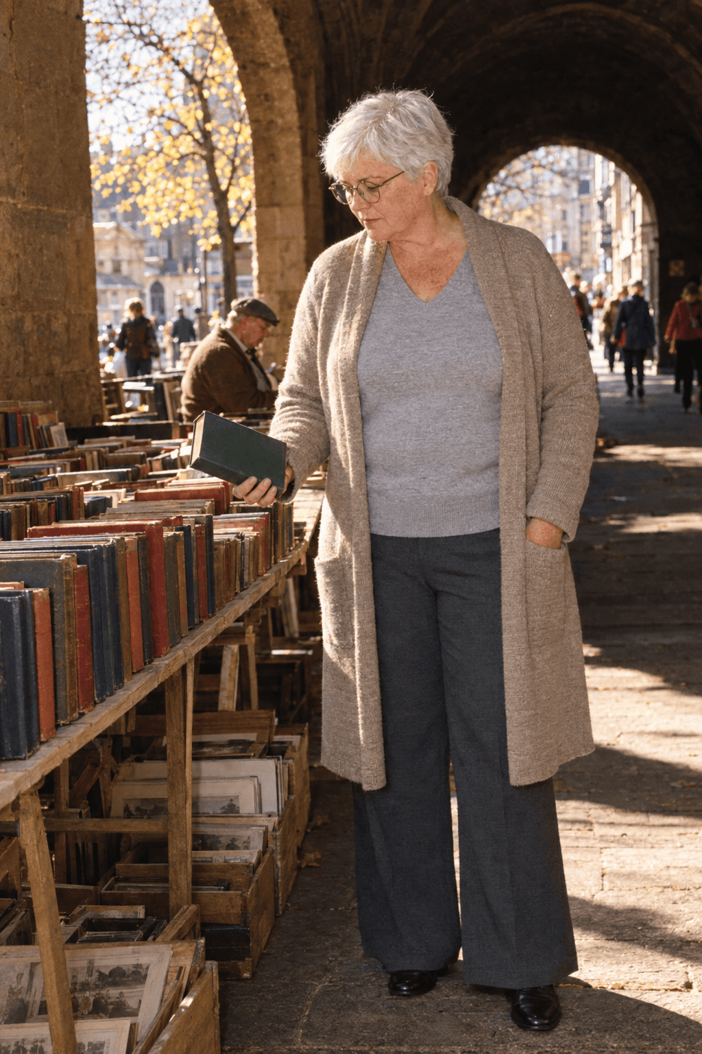 elegant plus size travel outfit for a woman in her 70s: khaki-oatmeal long knit duster, light gray cashmere V-neck, charcoal wide-leg ponte trousers and black loafers
