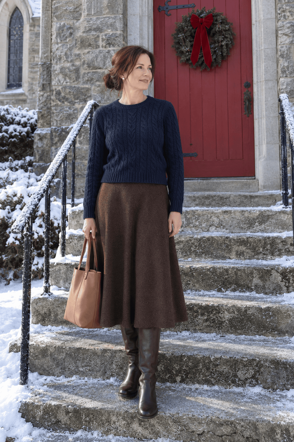 christmas morning church outfit for women: navy cable-knit crewneck sweater with a chocolate brown flared knit midi skirt and pearl stud earrings