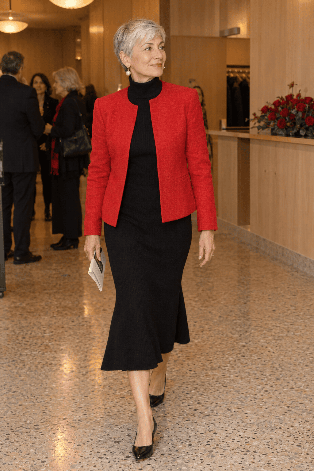 theater outfit for women over 60: black turtleneck knit midi dress with a hip-length poppy red collarless blazer, pearl drop earrings and black kitten heels