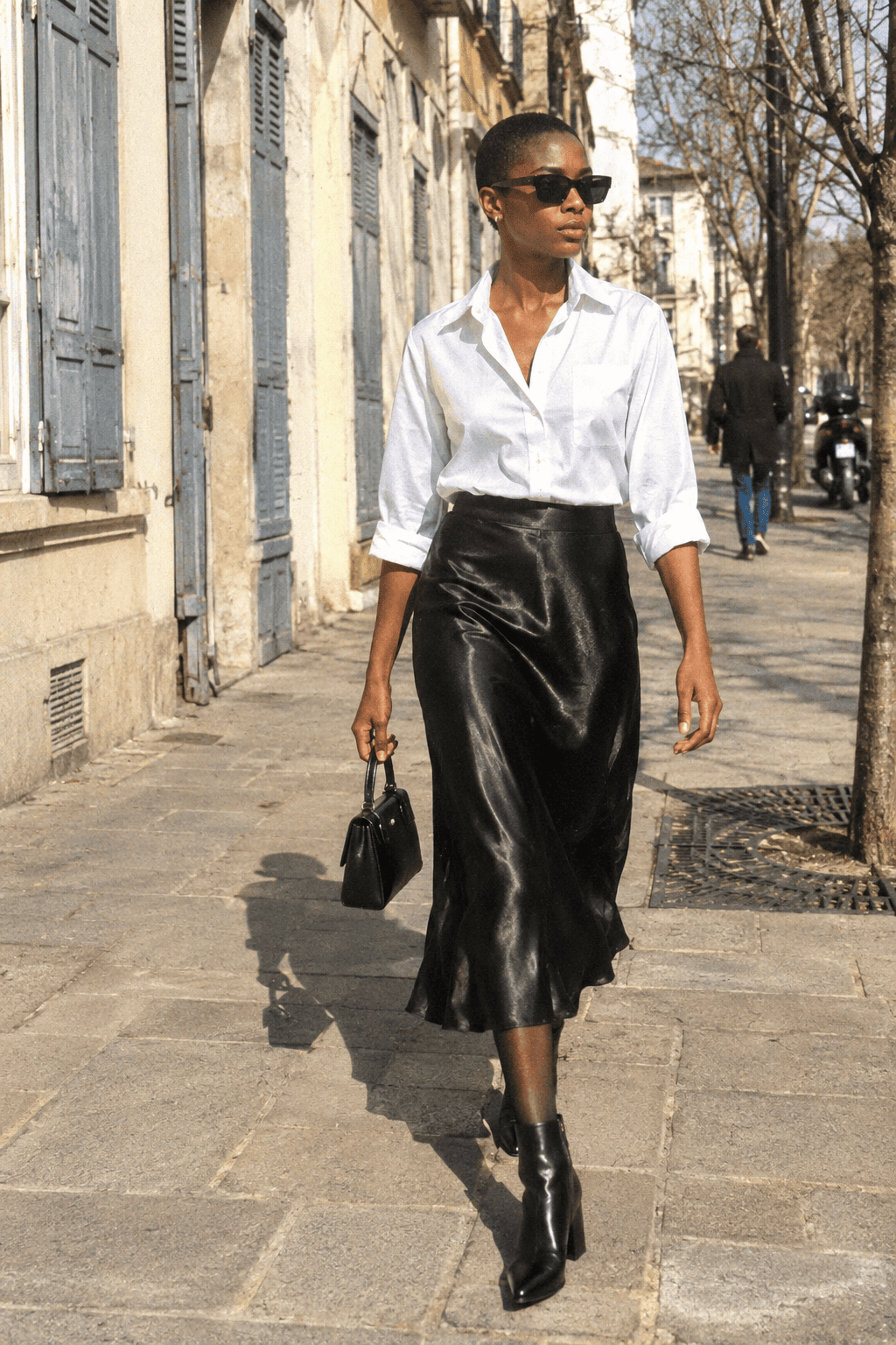 neutral capsule wardrobe dinner outfit: white cotton shirt tucked into a black slip midi skirt with black leather ankle boots
