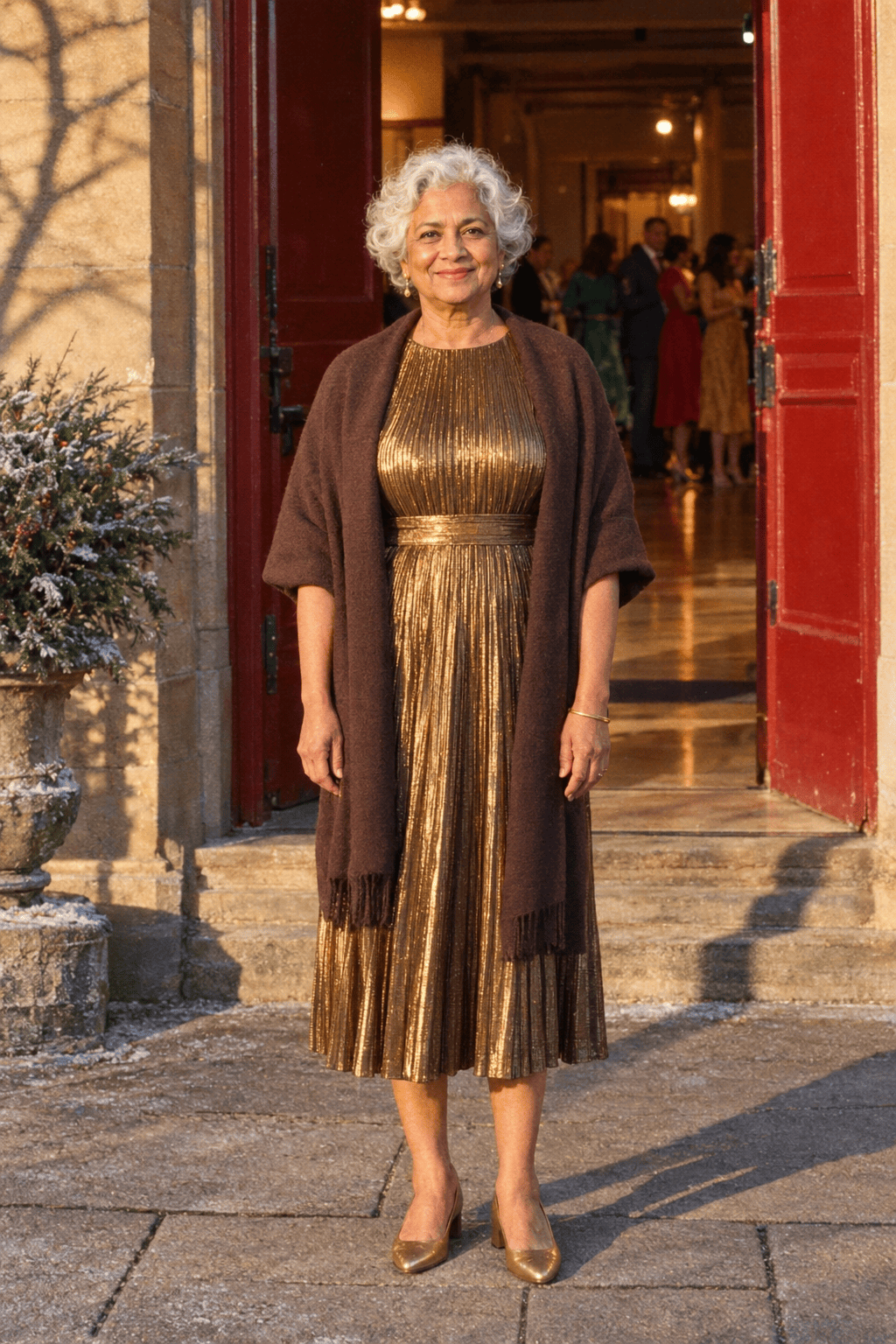 70th birthday party outfit: antique gold metallic pleated high-neck midi dress with a chocolate cashmere wrap around the shoulders and soft gold block-heel pumps