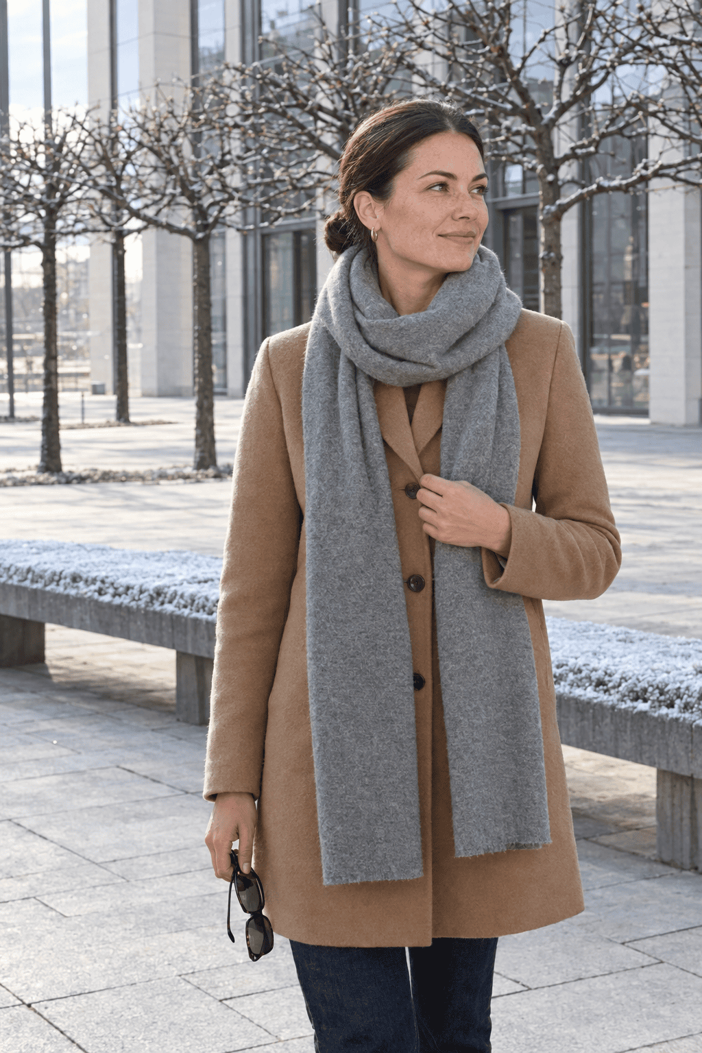 effortless winter outfits: woman in a large plain heather gray cashmere wrap over a camel wool coat and jeans