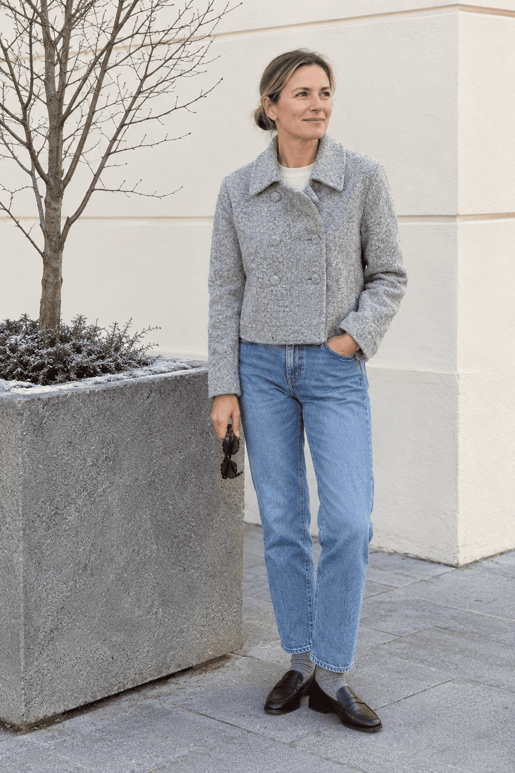 winter outfit for women over 40: grey bouclé cropped jacket, ivory cashmere crewneck, blue straight jeans and wine leather penny loafers