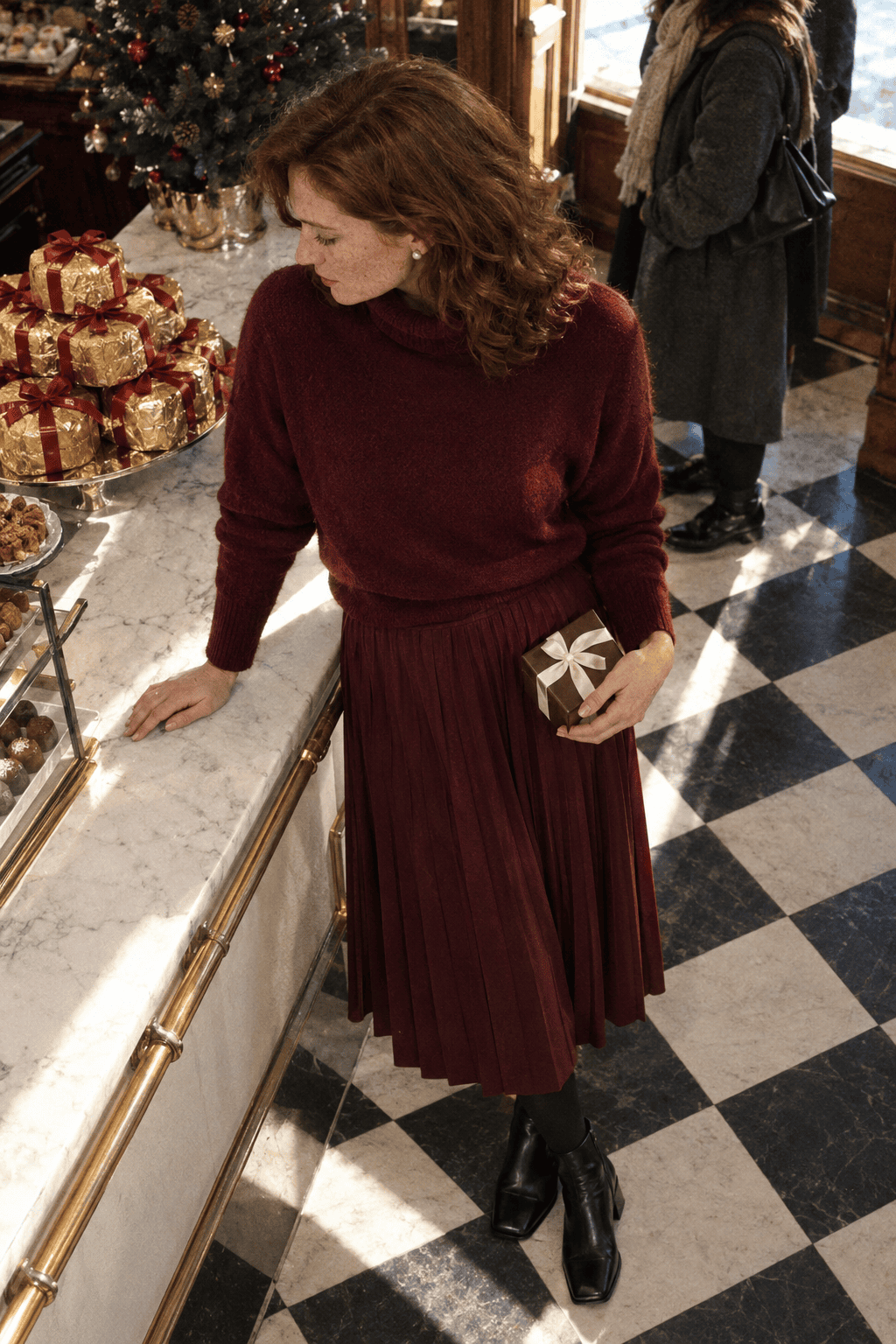 tonal burgundy christmas party outfit: wine pleated midi skirt, burgundy cashmere turtleneck and black leather ankle boots