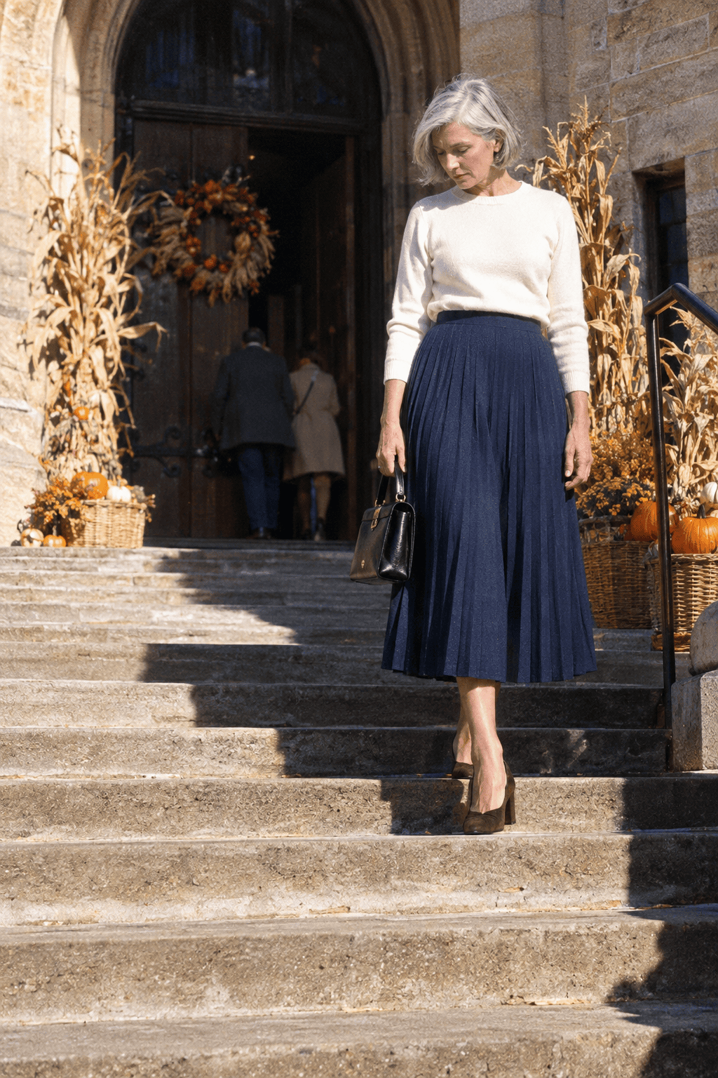 women over 60 thanksgiving outfit: navy pleated midi skirt with dark brown suede block-heel pumps
