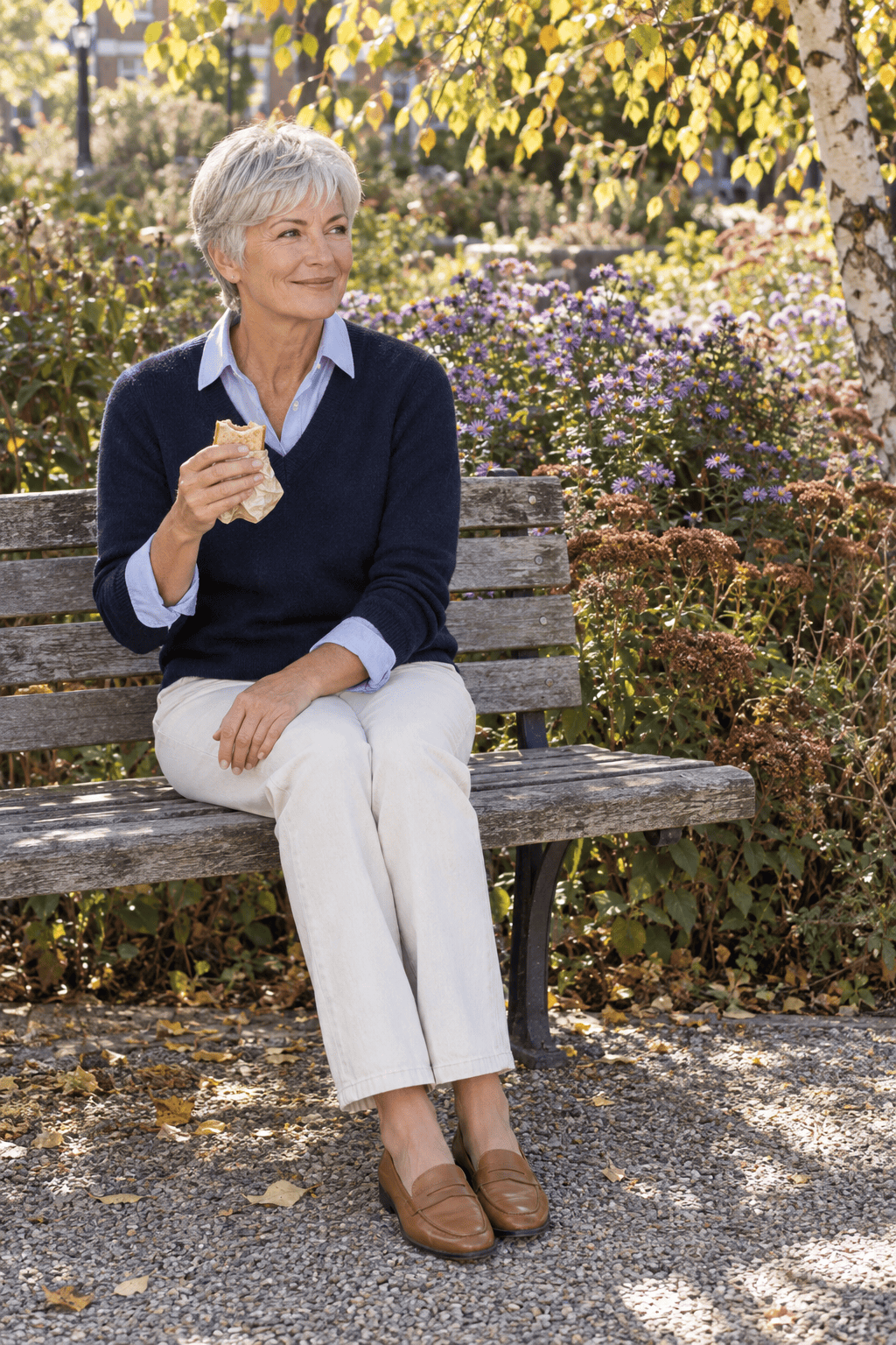 light blue oxford shirt under a navy V-neck sweater with winter-white straight jeans and tan penny loafers, a polished casual lunch outfit for women over 60