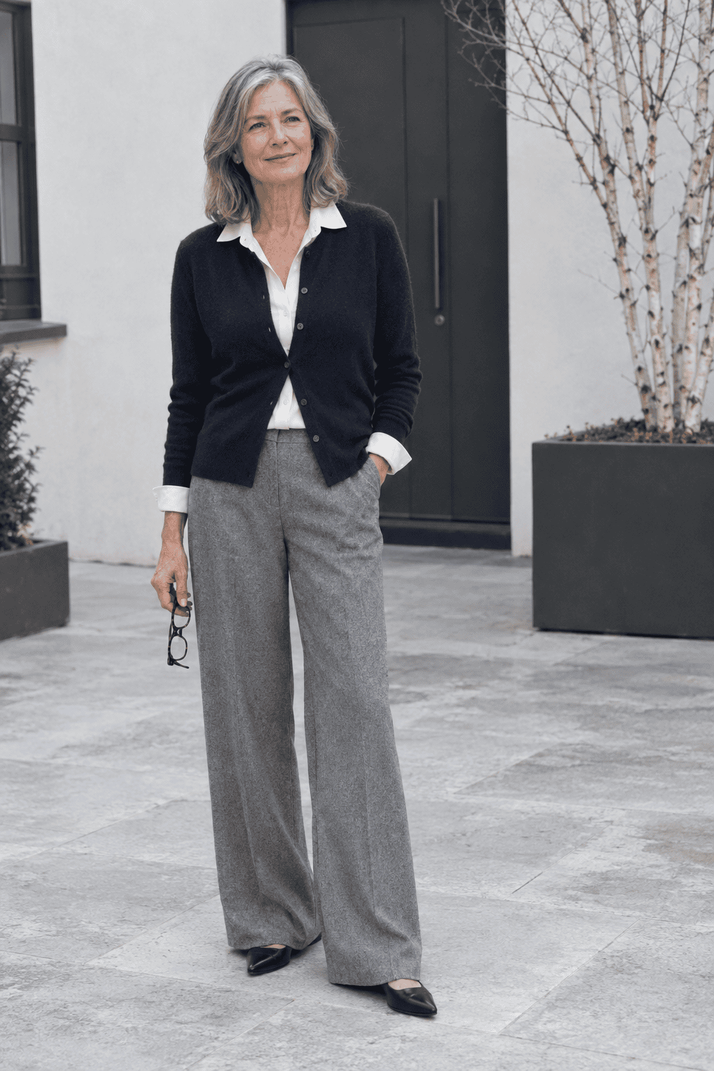 elegant cardigan outfit over 60: navy cashmere cardigan part-buttoned over an ivory silk notch-collar blouse with grey wool flannel trousers