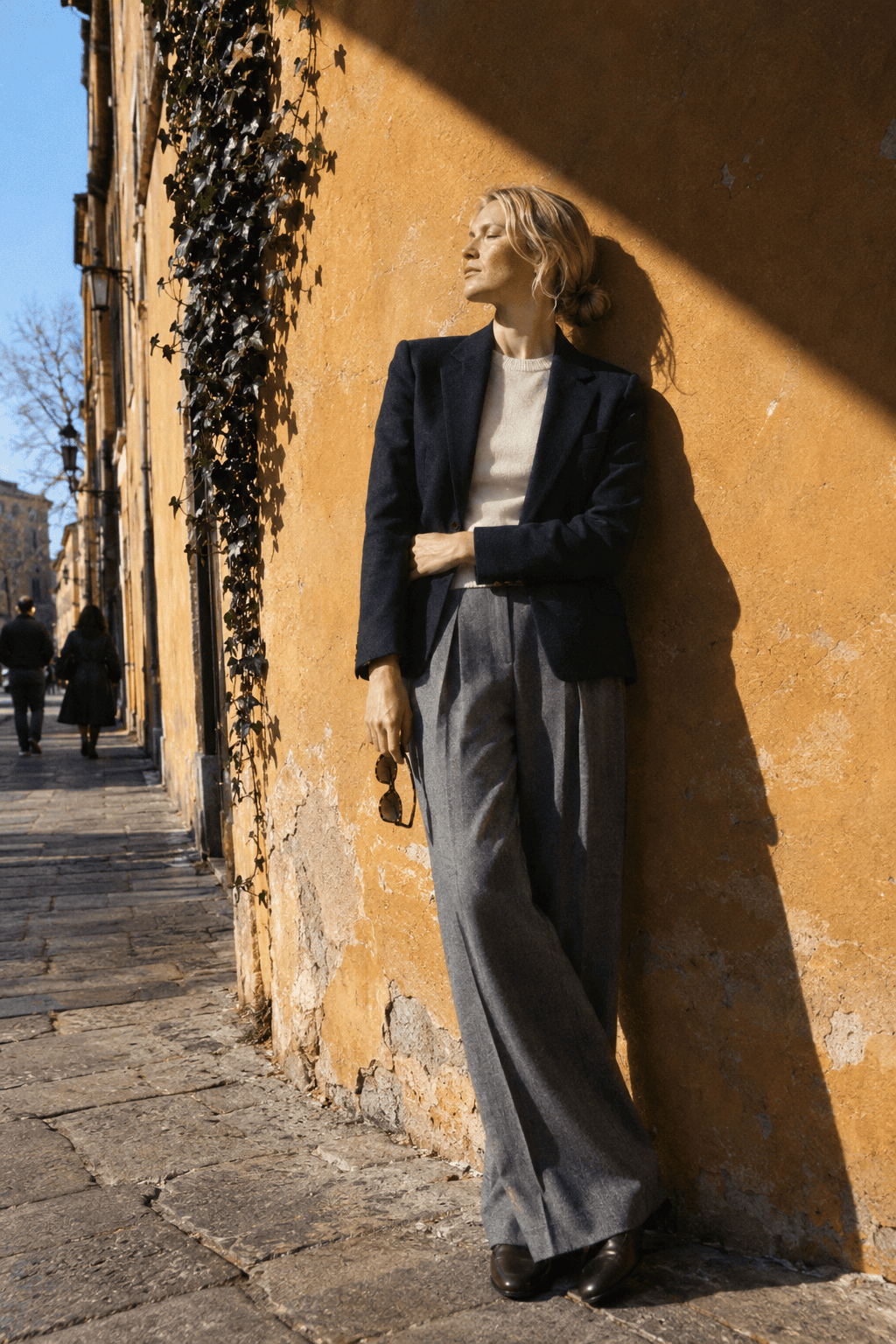 capsule wardrobe meeting outfit: navy wool blazer over an ivory cashmere crewneck with grey pleated trousers and dark brown loafers