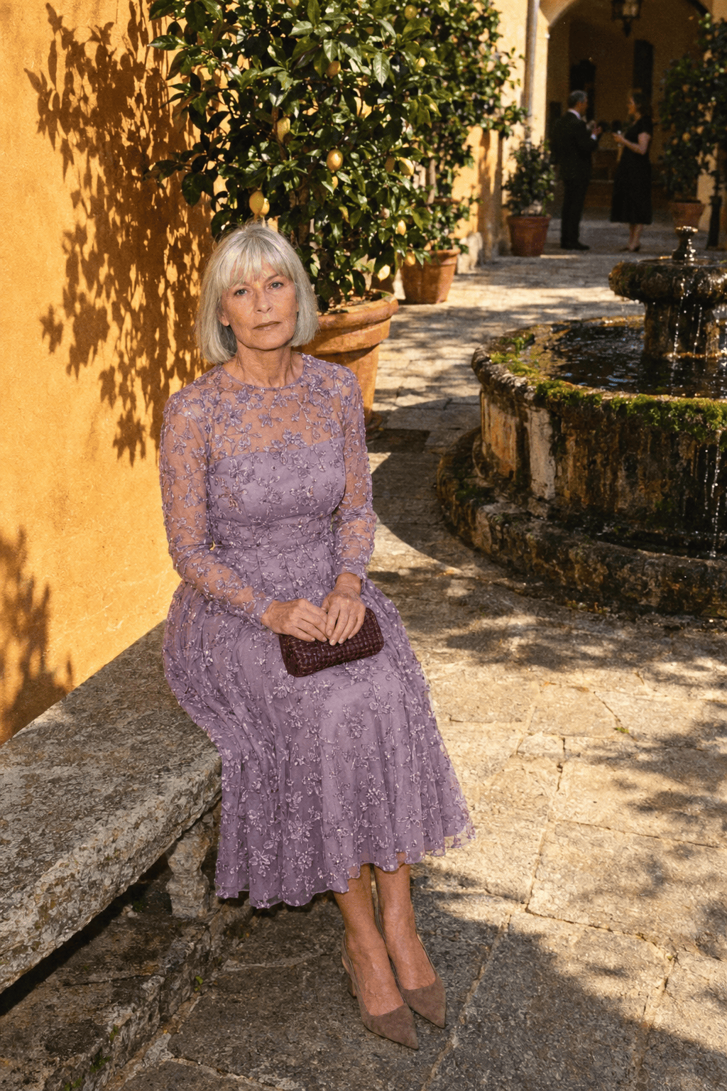 courtyard cocktail wedding guest outfit for women in their 70s: soft mauve embroidered long-sleeve tea-length dress with taupe kitten slingbacks and a burgundy woven clutch