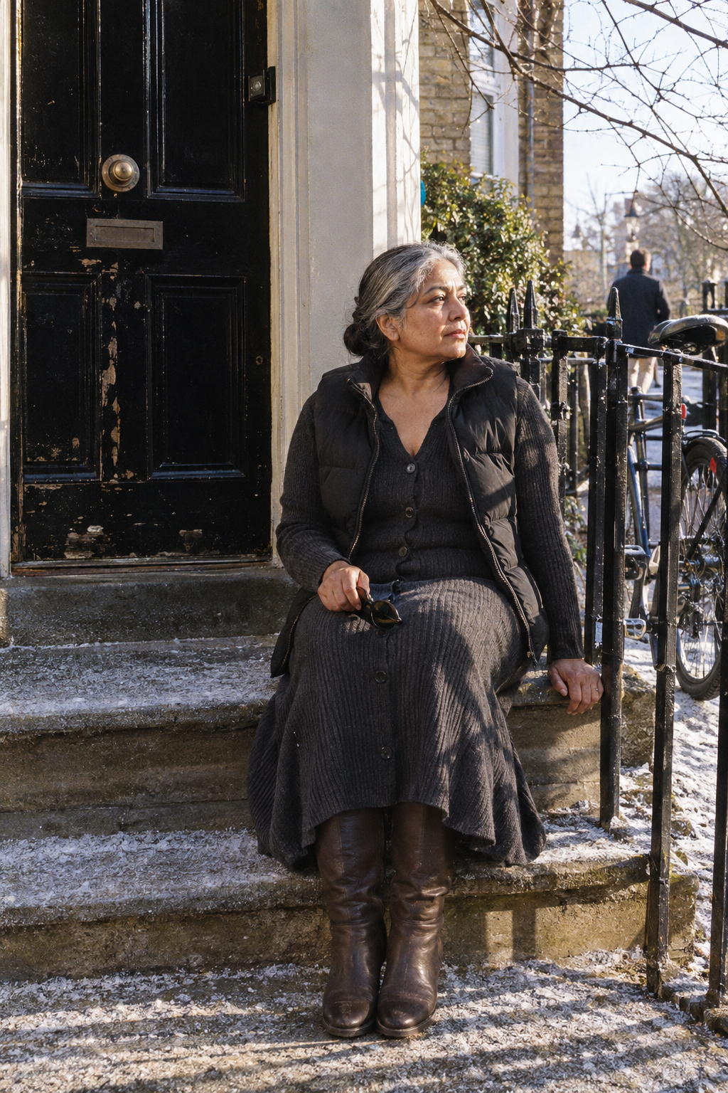 women over 60 winter outfit: charcoal ribbed sweater dress, black compact puffer vest and chocolate brown flat stretch knee-high boots
