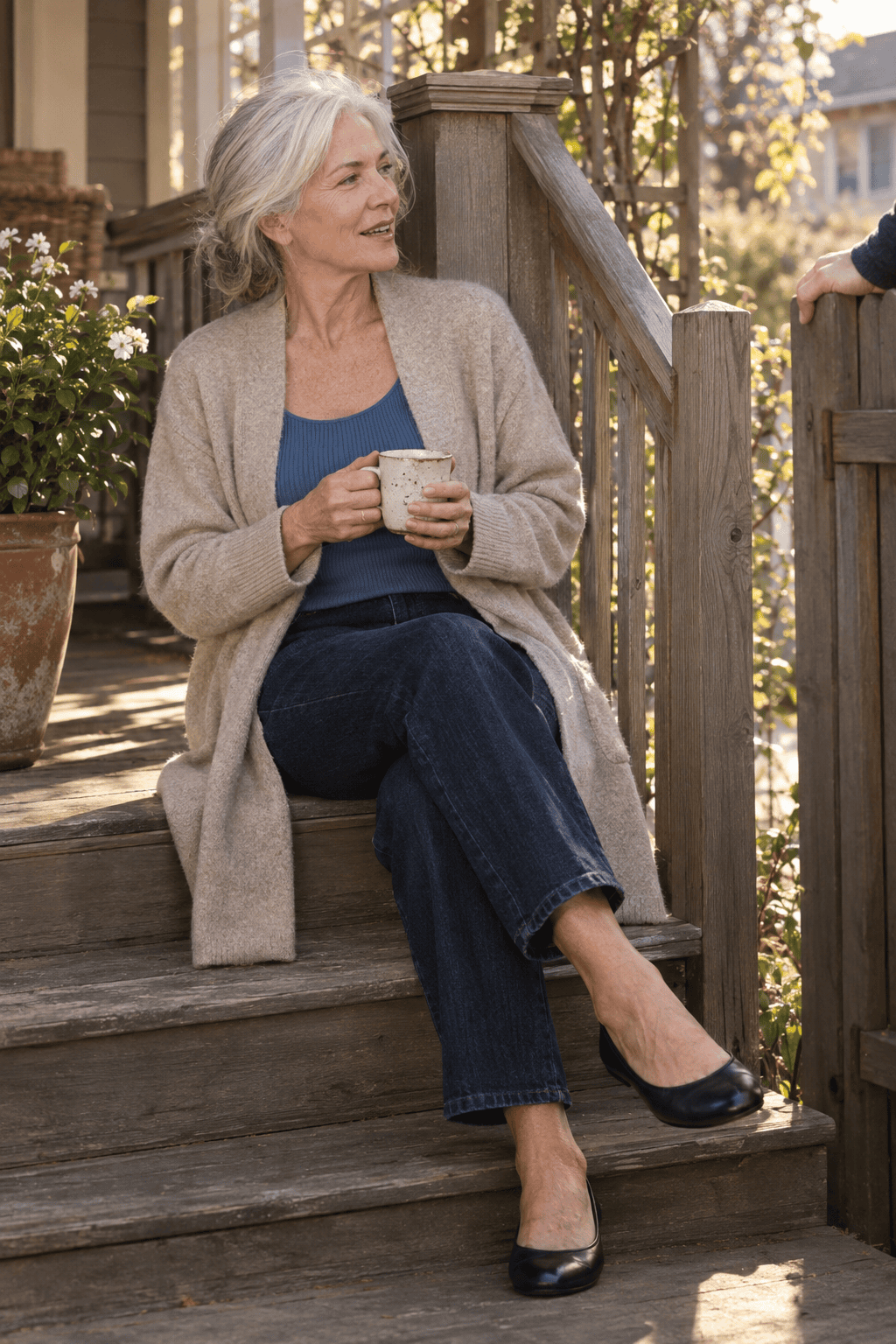 spring outfit for women over 70: oatmeal cashmere duster cardigan over a blue tank and dark indigo straight jeans