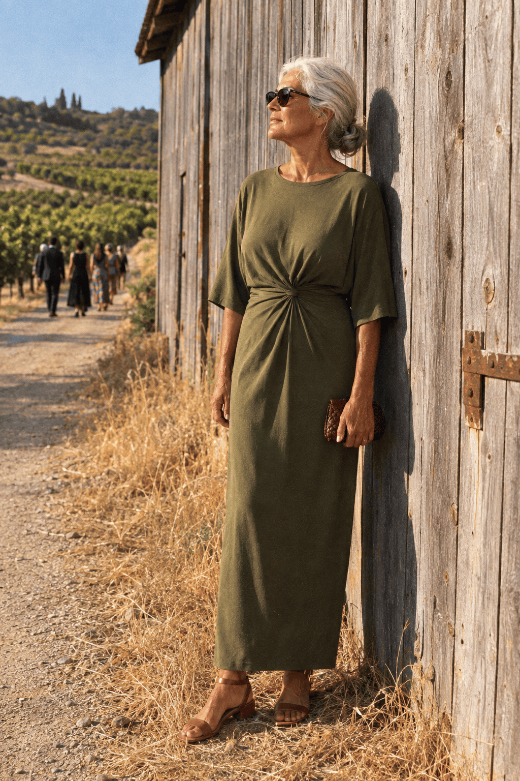rustic vineyard wedding guest outfit for women in their 70s: olive green elbow-sleeve jersey column midi dress with low tan sandals and a burgundy woven clutch
