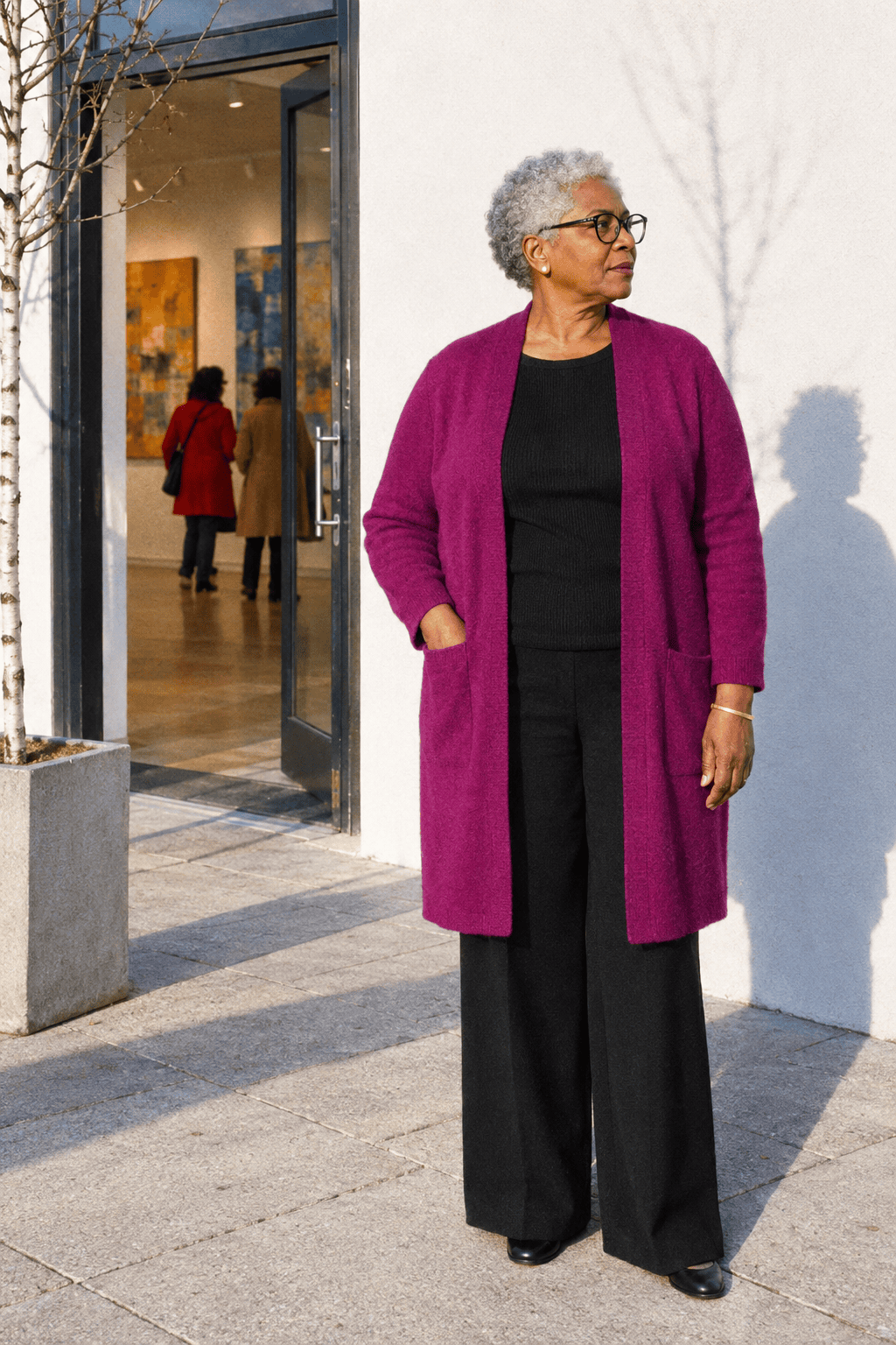 elegant plus size winter dinner outfit for a woman in her 70s: berry purple long knit duster worn open over a black shell, black wide-leg ponte trousers and black pumps