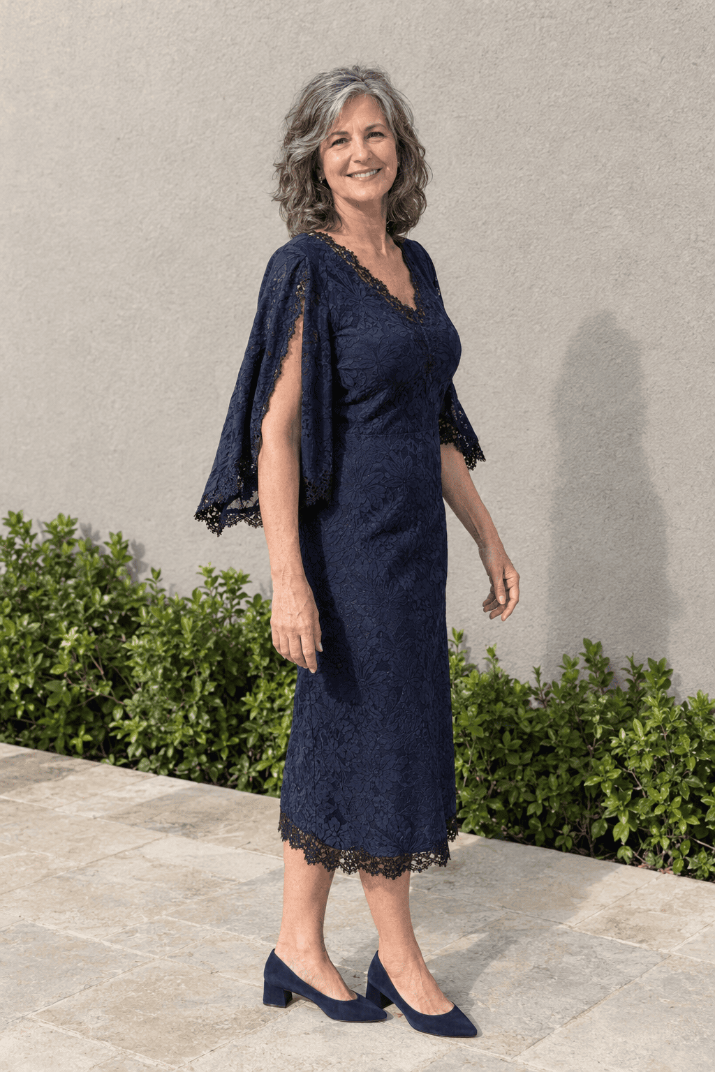 mother of the bride outfit in navy: jacquard and black lace cape-sleeve midi dress with navy suede block-heel pumps