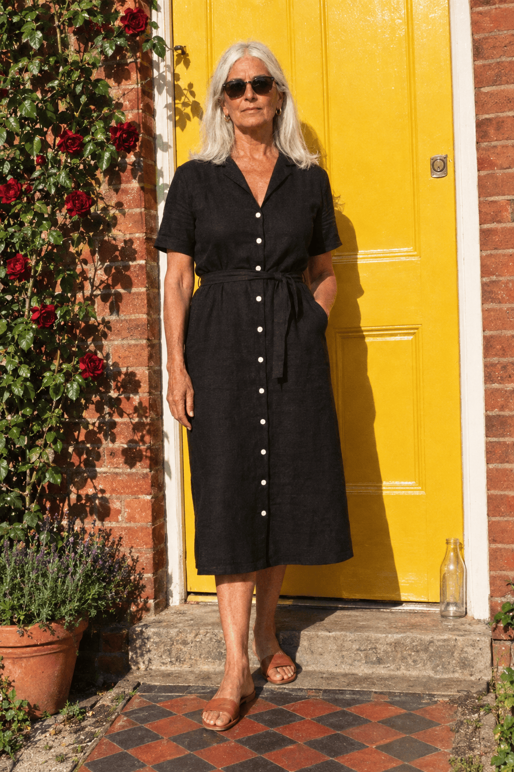 elegant summer dinner outfit for a woman in her 70s on a budget: black linen button-front midi dress with short sleeves and cognac leather slide sandals