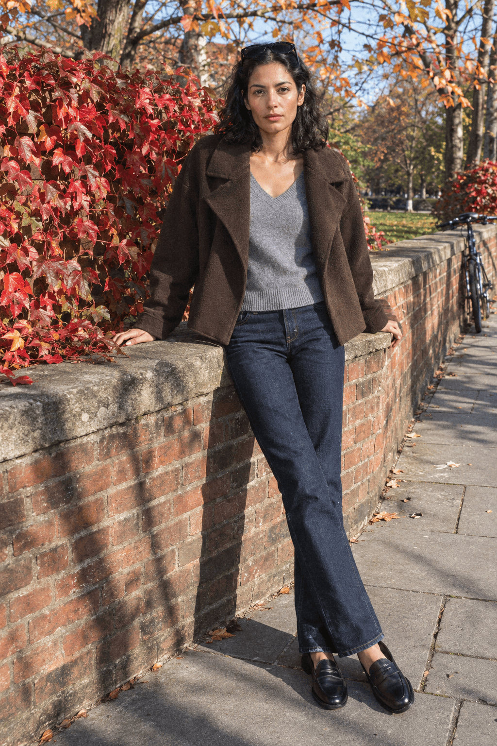 Is Massimo Dutti a good brand: woman in a brown wool coat, grey sweater and dark jeans in fall sun